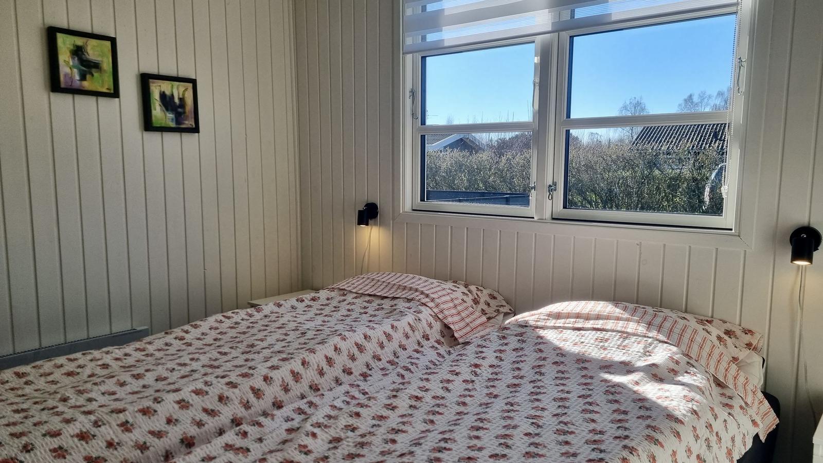 Schlafzimmer mit Bett, Fenster und Wandbildern.