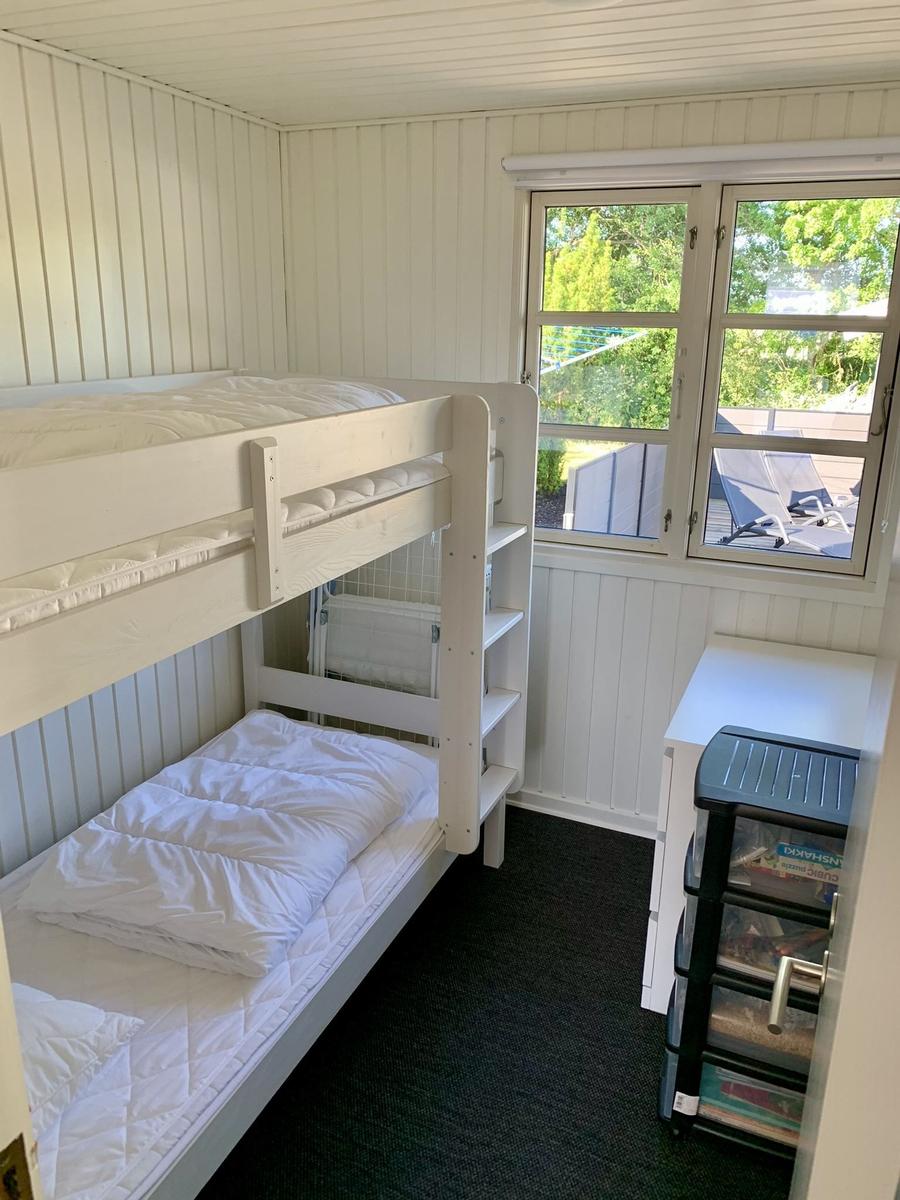 Zimmer mit Doppelstockbett, Fenster und Schreibtisch.