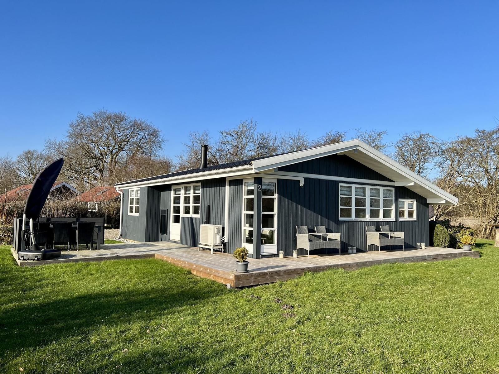 Ein modernes Haus mit Terrasse und Garten. Möblierte Außenterrasse mit Sitzgelegenheiten.