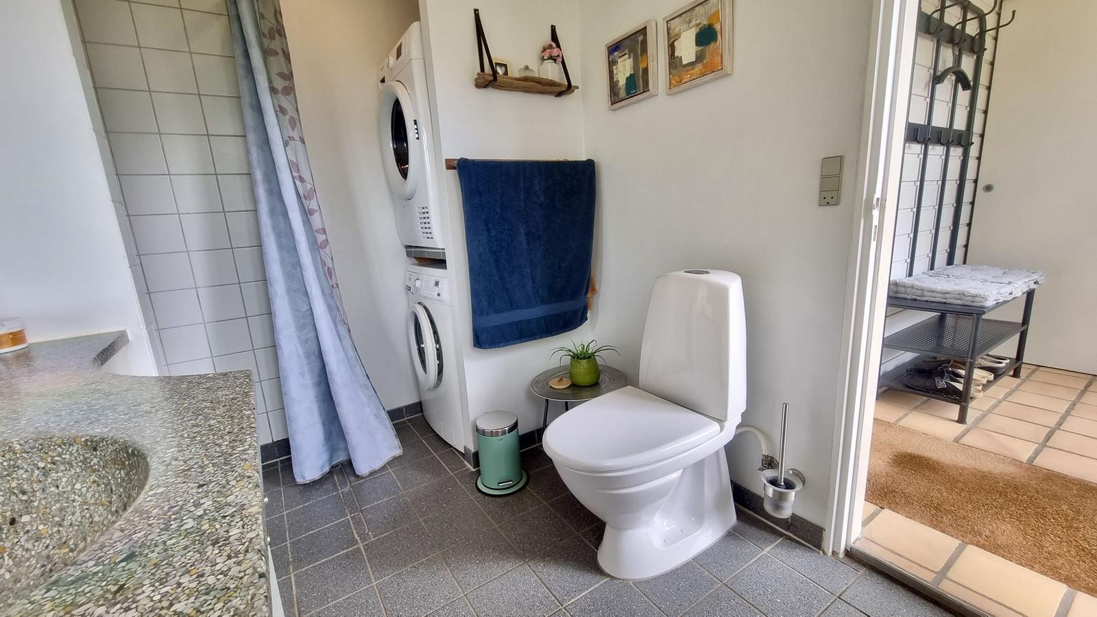 Bad mit Toilette, Waschmaschine und Duschbereich.