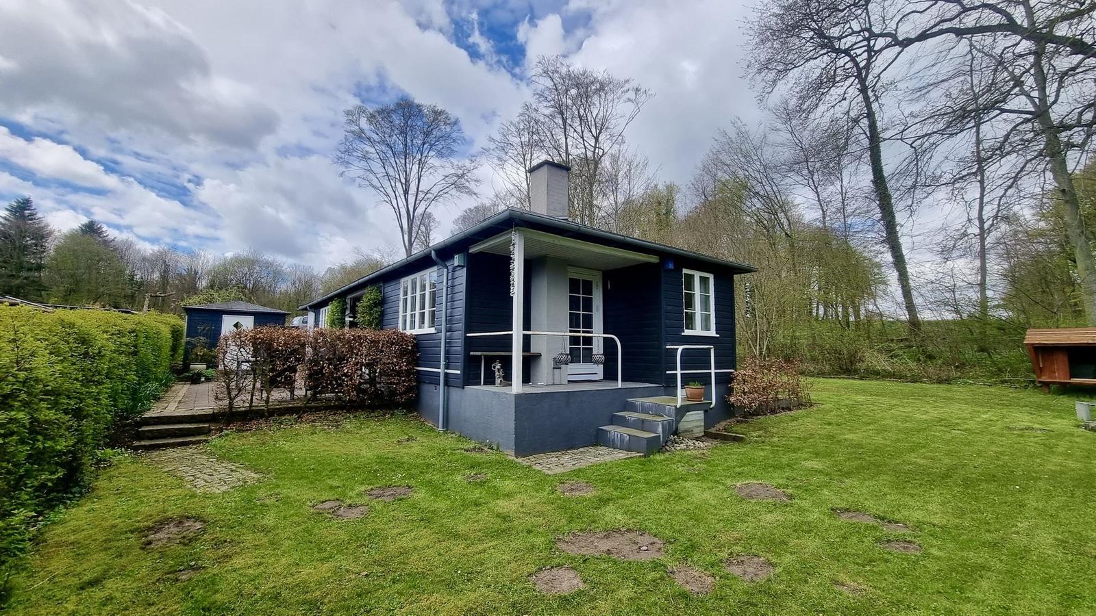 Ein dunkelblaues Haus mit weißem Vordach und Rasenfläche.