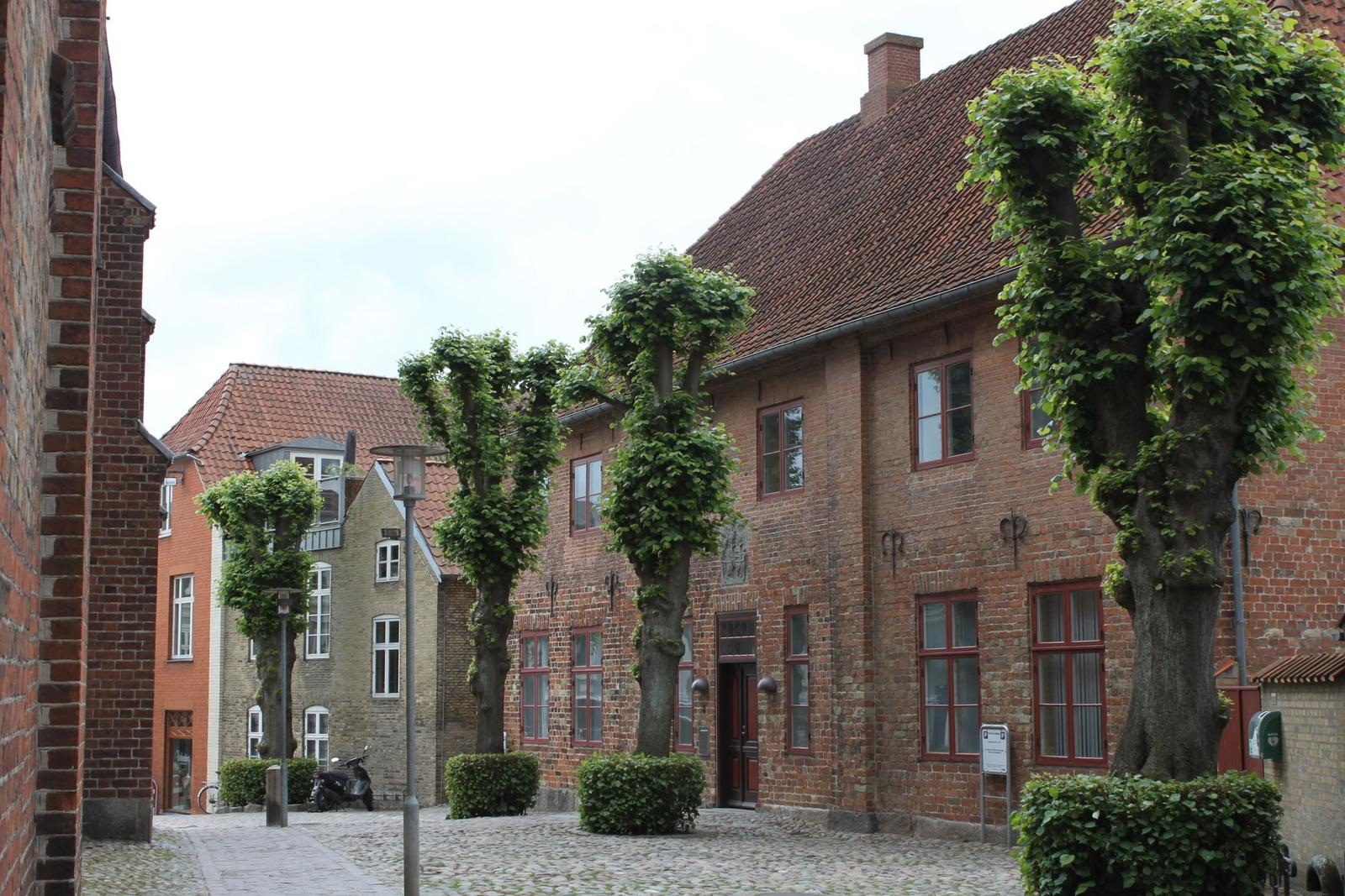 Historisches Gebäude mit rotem Ziegeldach und geschmückten Bäumen im Hof.