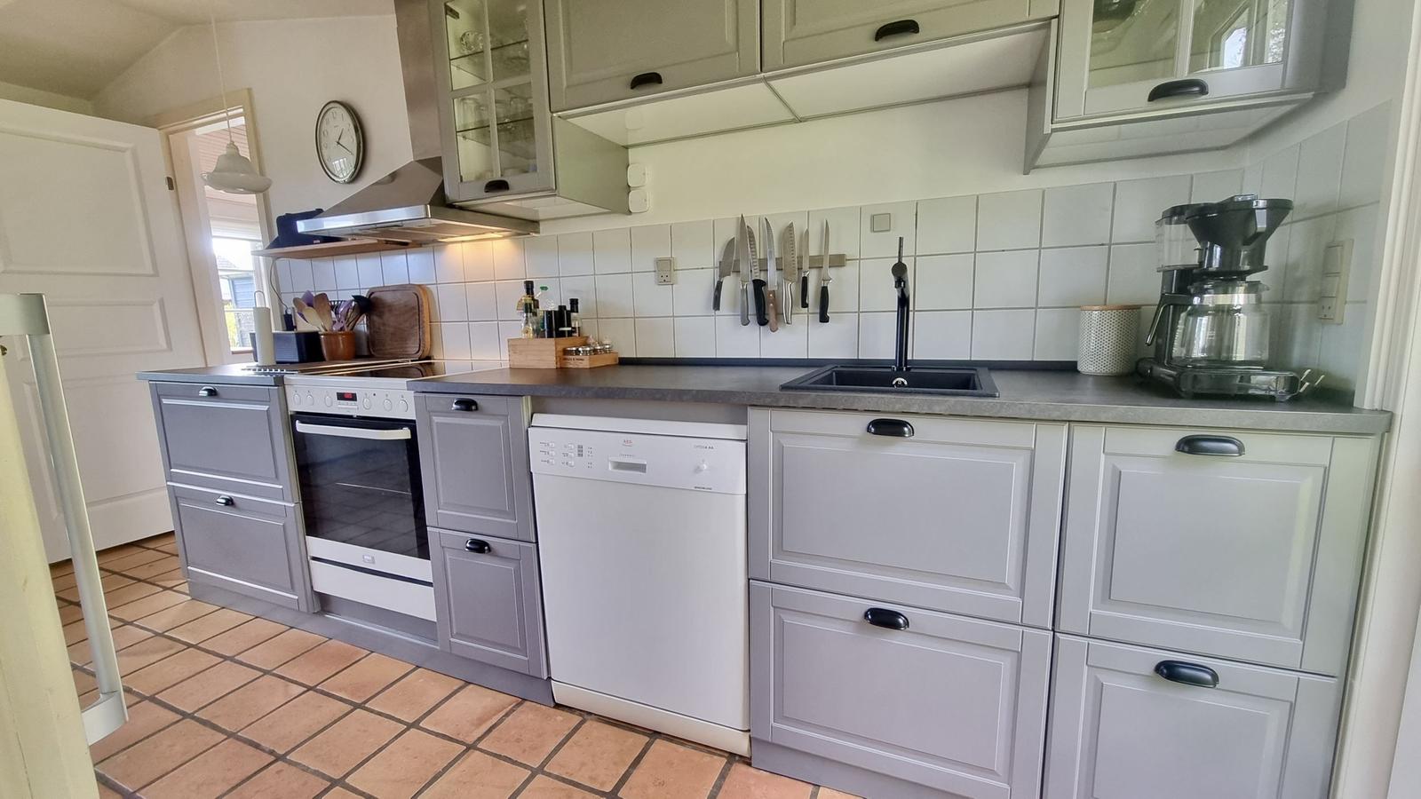 Küche mit grauen Schränken, Spüle, Kühlschrank und Kochfeld.