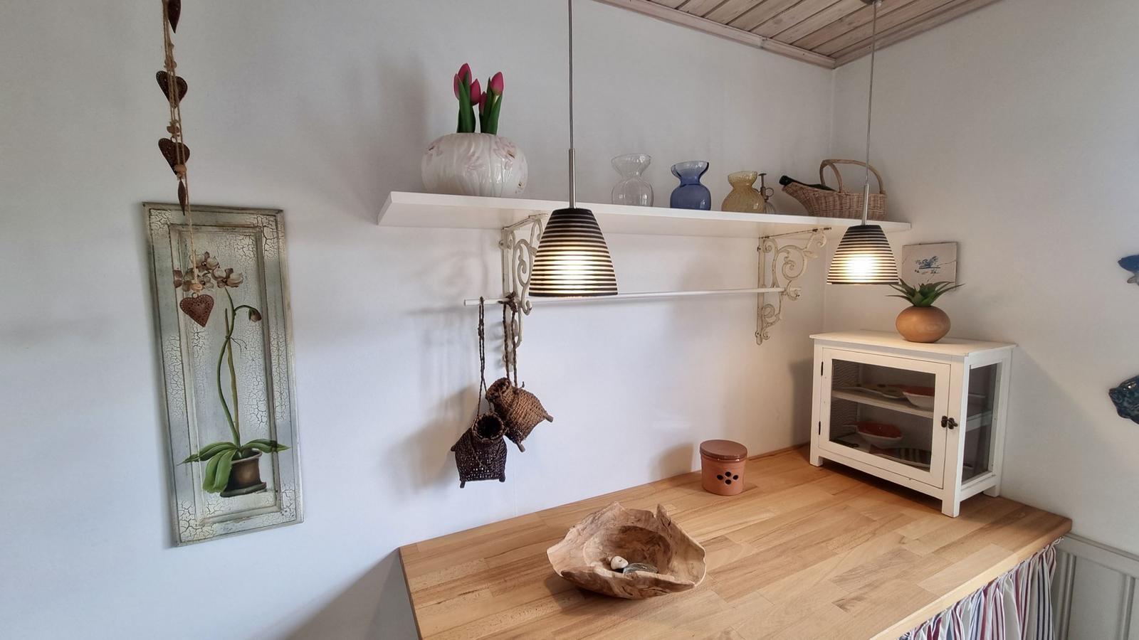 Holzoberfläche mit Schale, Wandregal und Lampen. Weiße Wände und Dekoration.