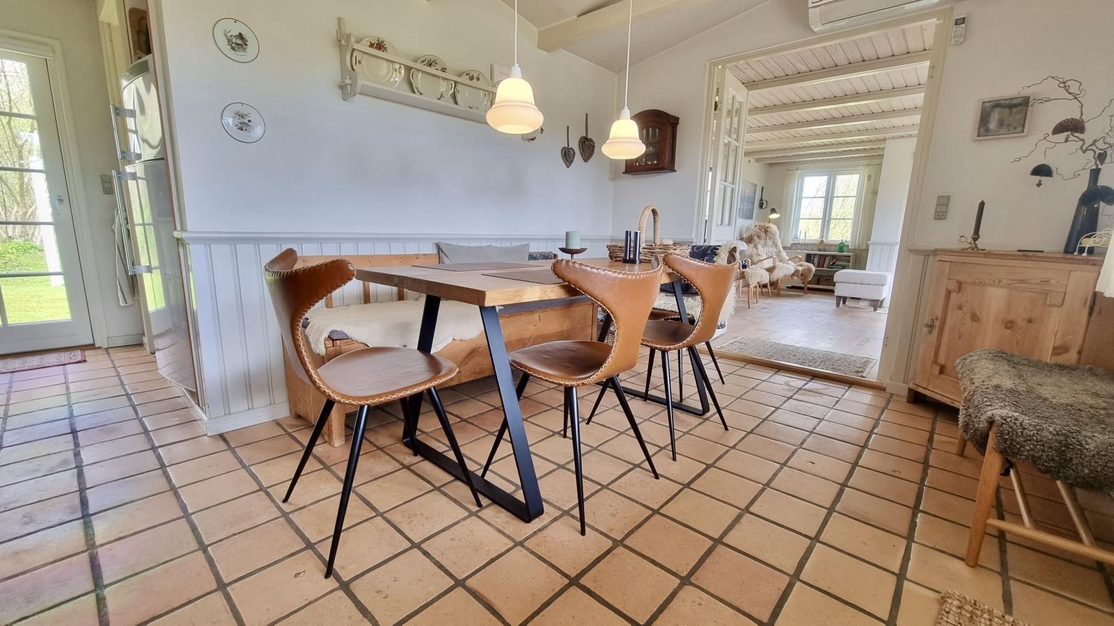 Essbereich mit Holztisch, Lederstühlen und Terrakottaboden. Blick in Wohnzimmer mit Holzfußboden.