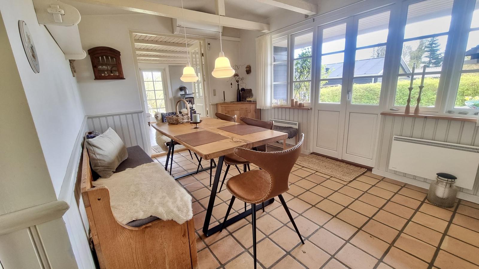 Essbereich mit Holztisch, Ledersitzen und großem Fensterblick.