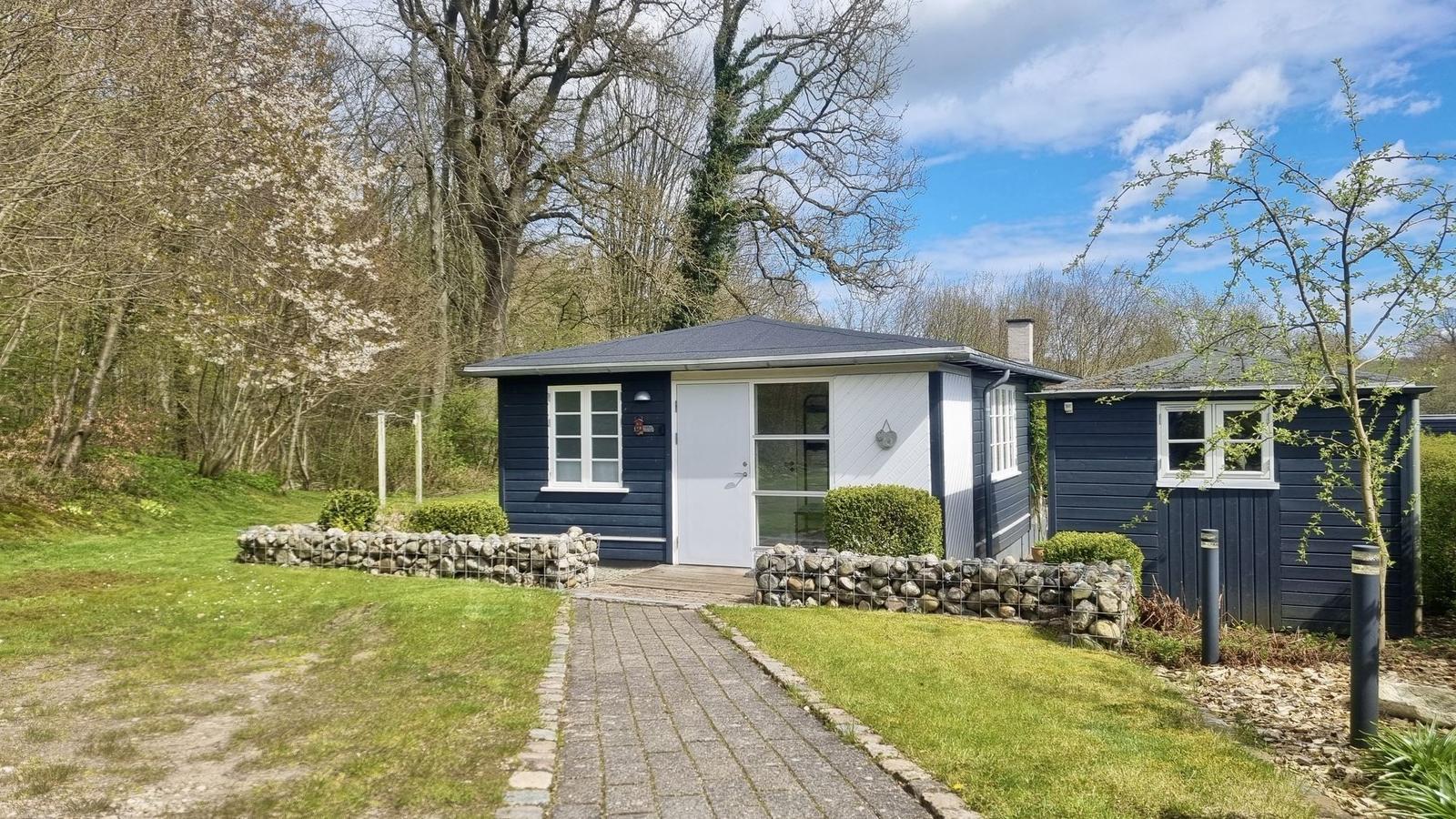 Ein kleines Haus mit blauen Wänden und weißer Tür. Vor dem Haus führt ein gepflasterter Weg.