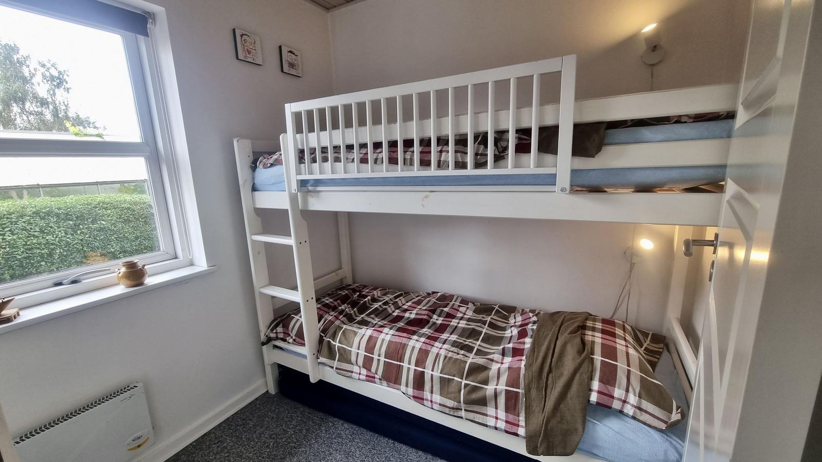 Zimmer mit Doppelstockbett, Fenster und Heizung.