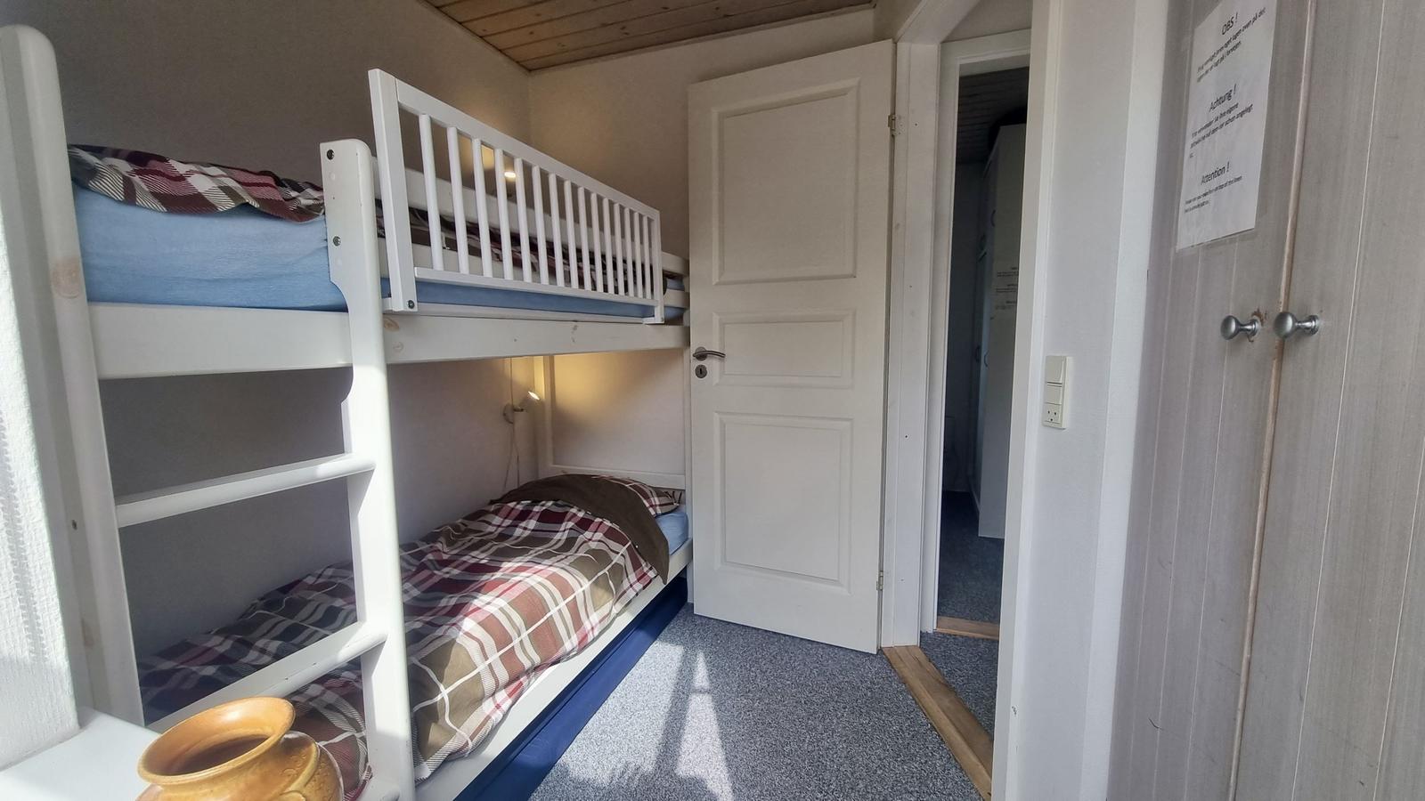 Zimmer mit Doppelstockbett und Tür zum Flur.