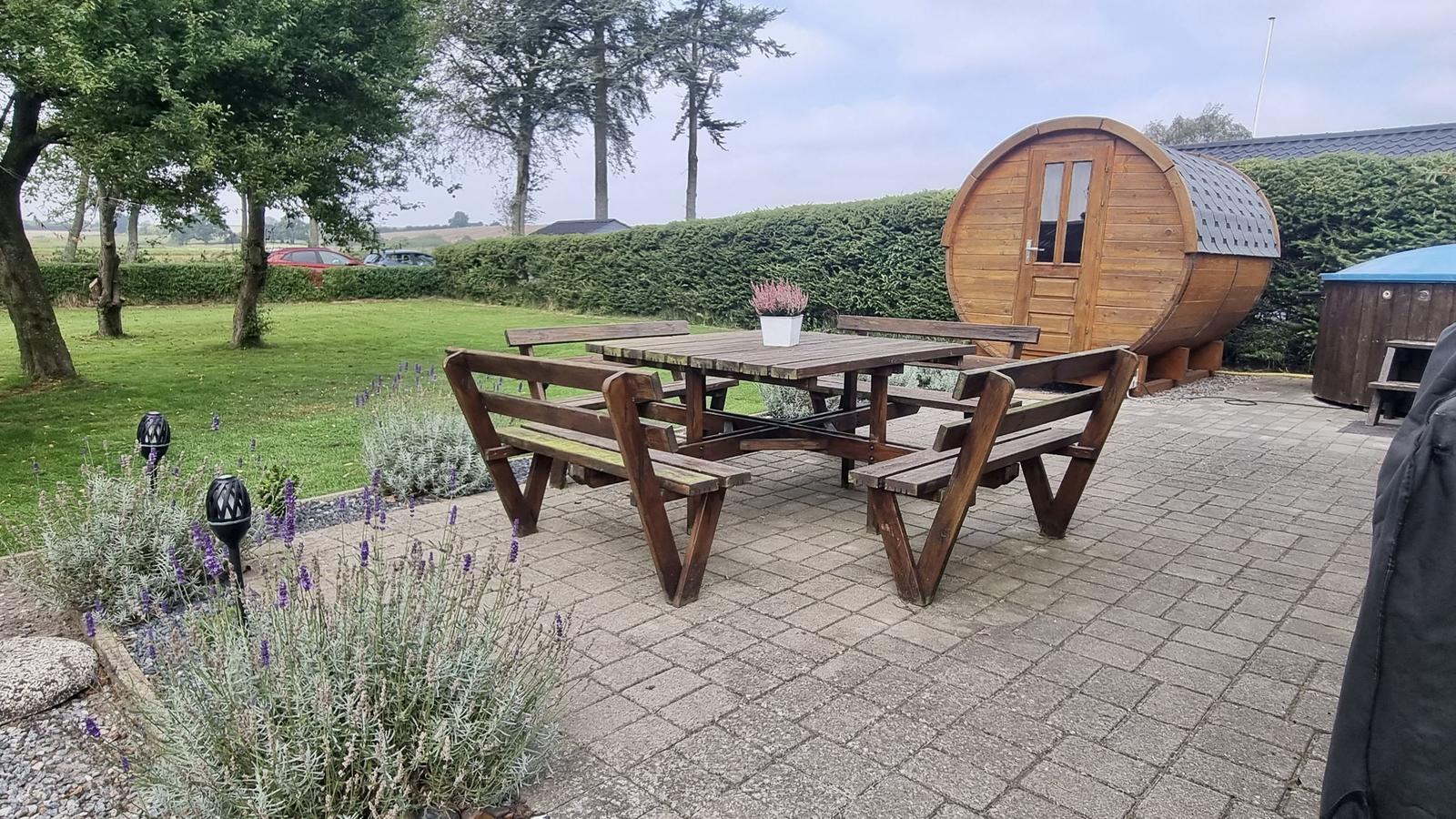 Holztisch mit Bänken auf gepflastertem Bereich neben Holzbarrique