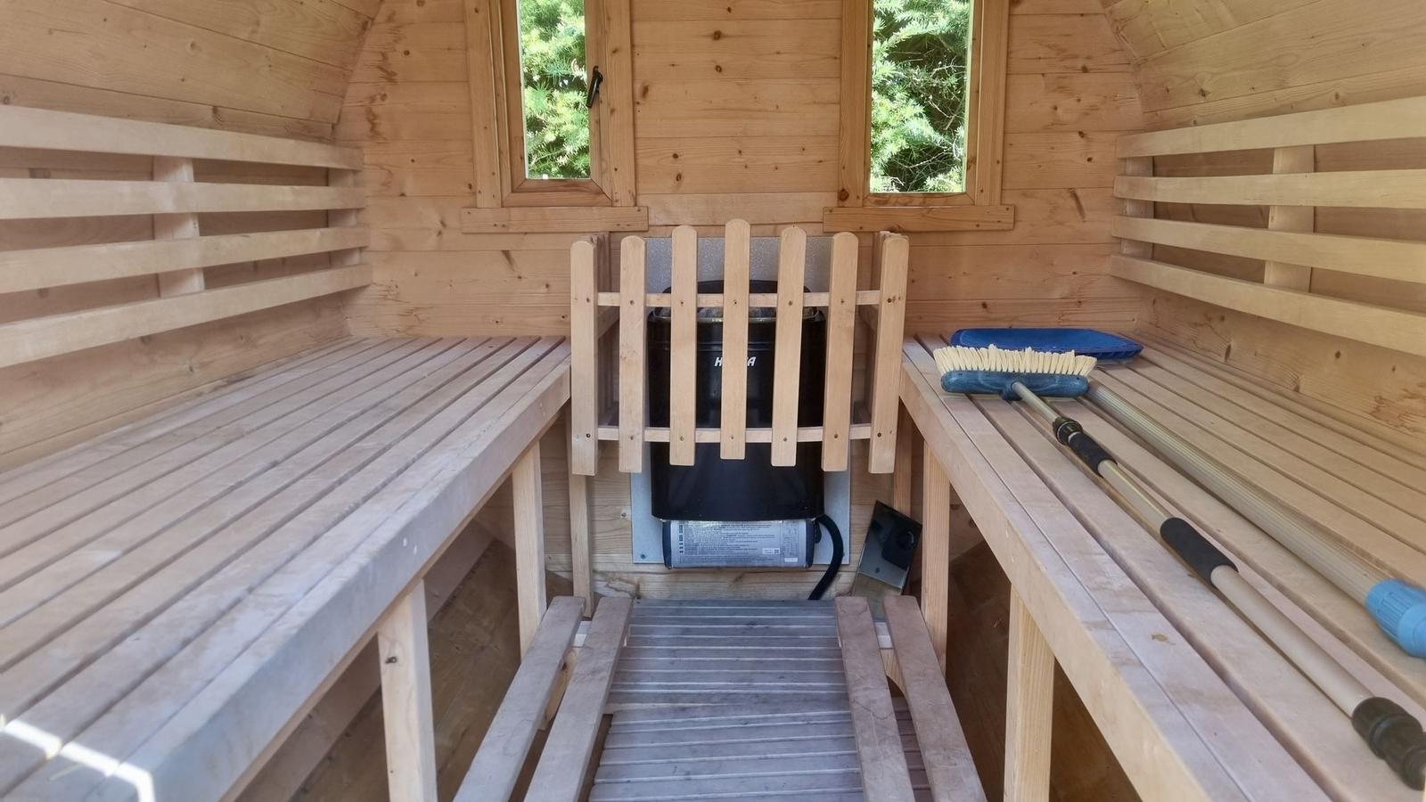 Sauna mit Holzbänken, Ofen und Fenstern zur Aussicht.