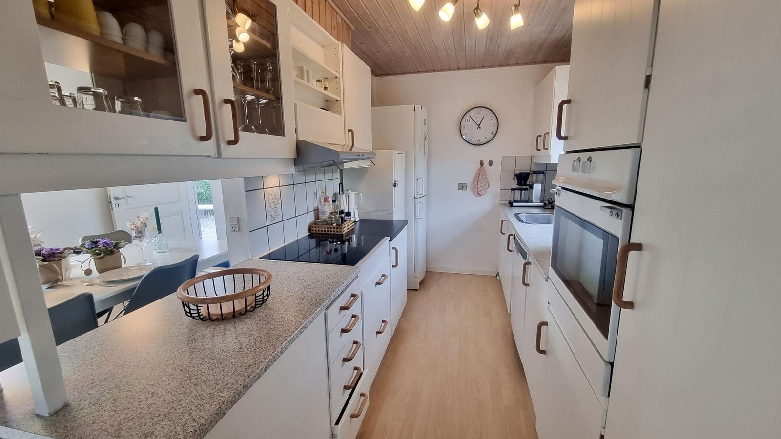 Küche mit weißen Schränken, schwarzer Arbeitsplatte und integriertem Ofen.