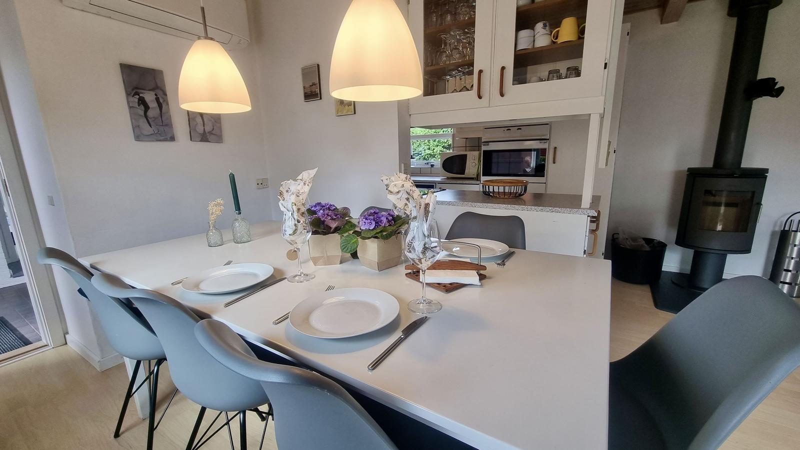 Essbereich mit Tisch, Stühlen und Küchenbereich im Hintergrund.