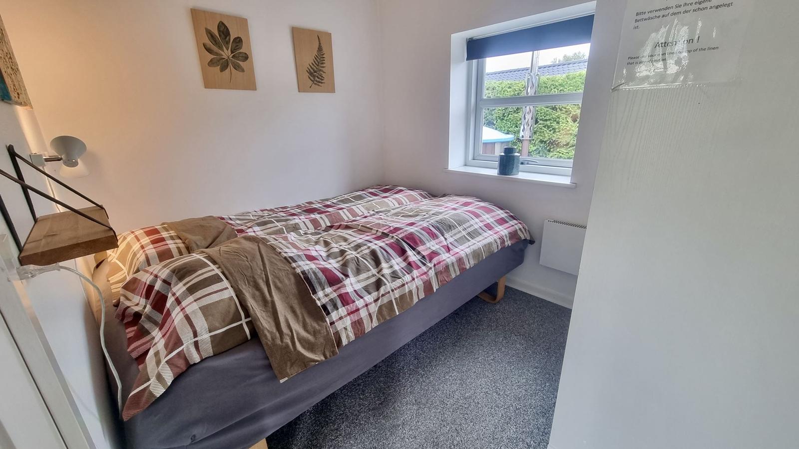 Ein Schlafzimmer mit einem Bett, Fenster und Wanddekoration.