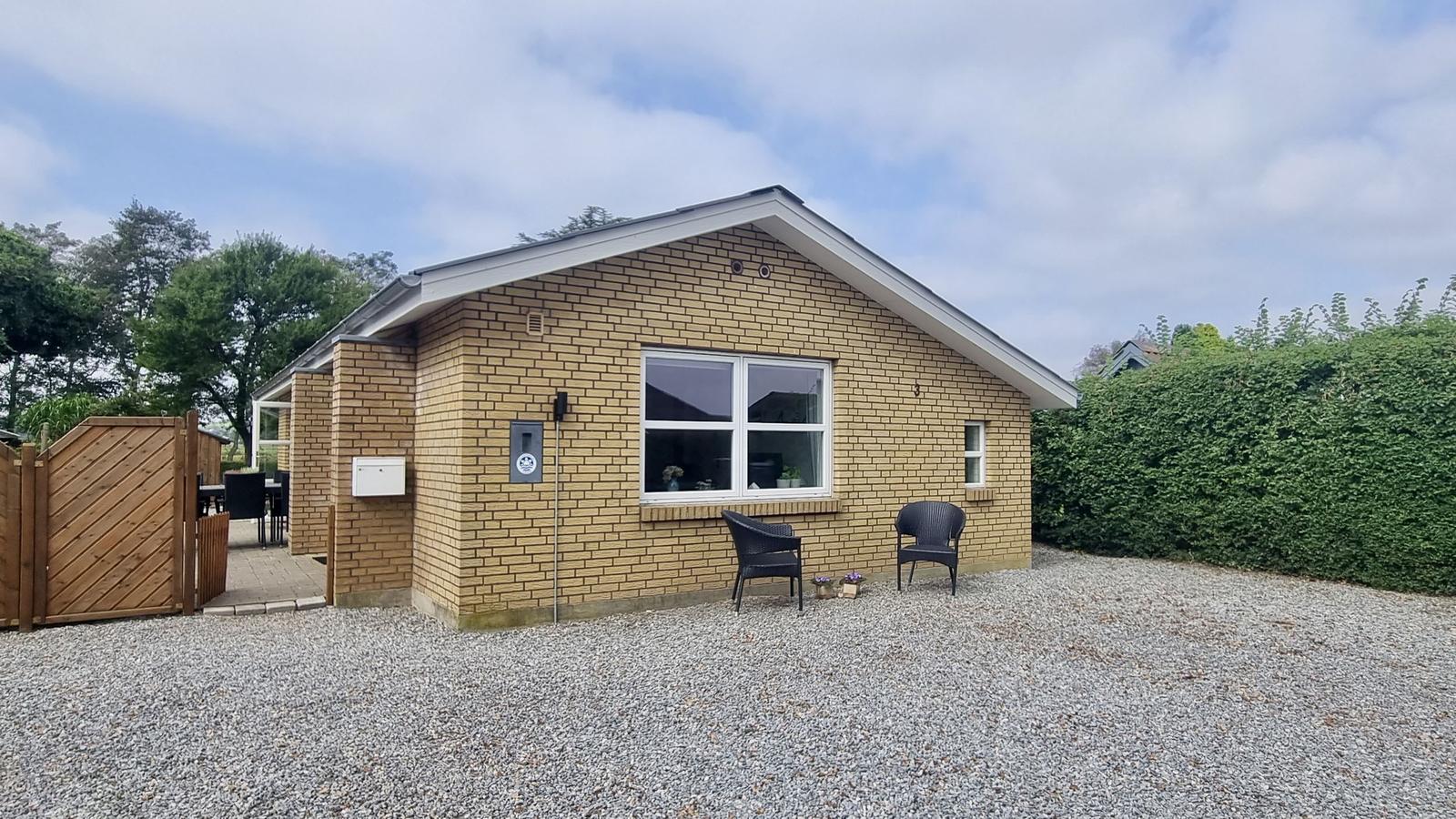 Ein kleines Haus mit Steinmauer, zwei Stühlen und einem Holzzaun.