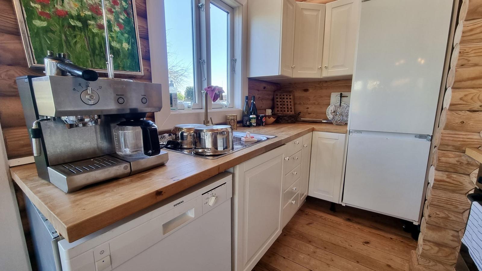 Küche mit Holzoberflächen, weißer Küchenzeile und integriertem Kühlschrank.