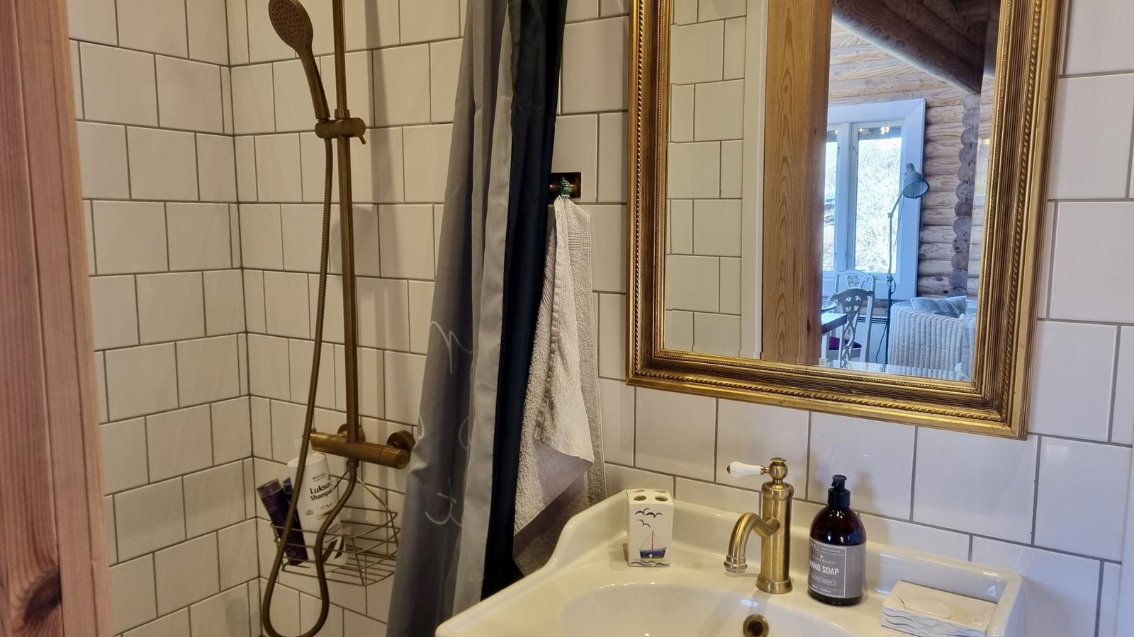 Badezimmer mit Dusche, Waschbecken und Spiegel