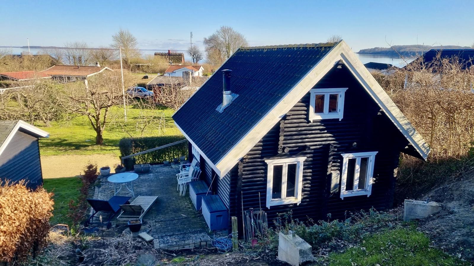 Schwarzes Holzhaus mit Terrasse und Blick auf Wasser