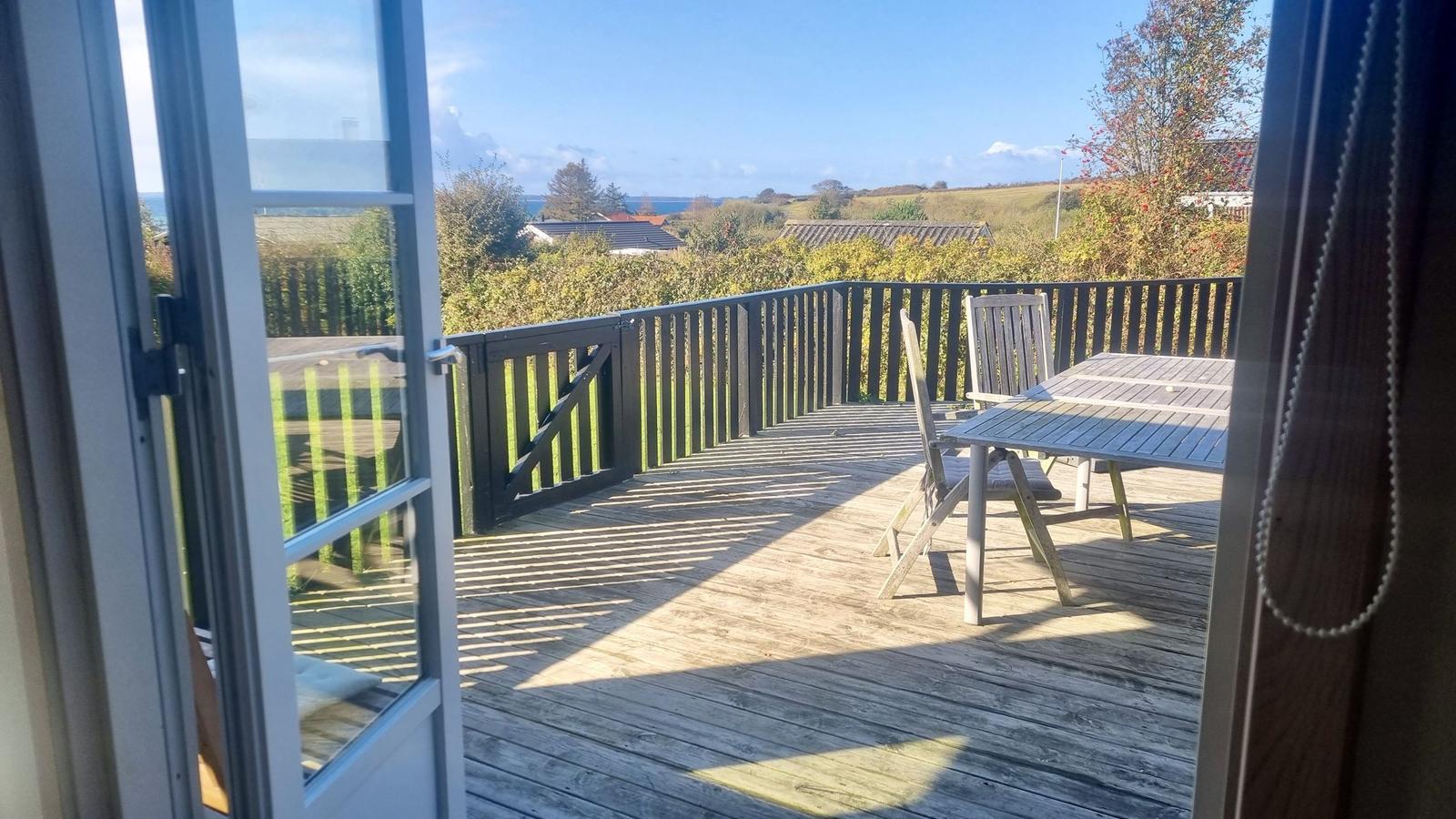 Terrasse mit Tisch und Stühlen, Blick auf Landschaft und Meer.