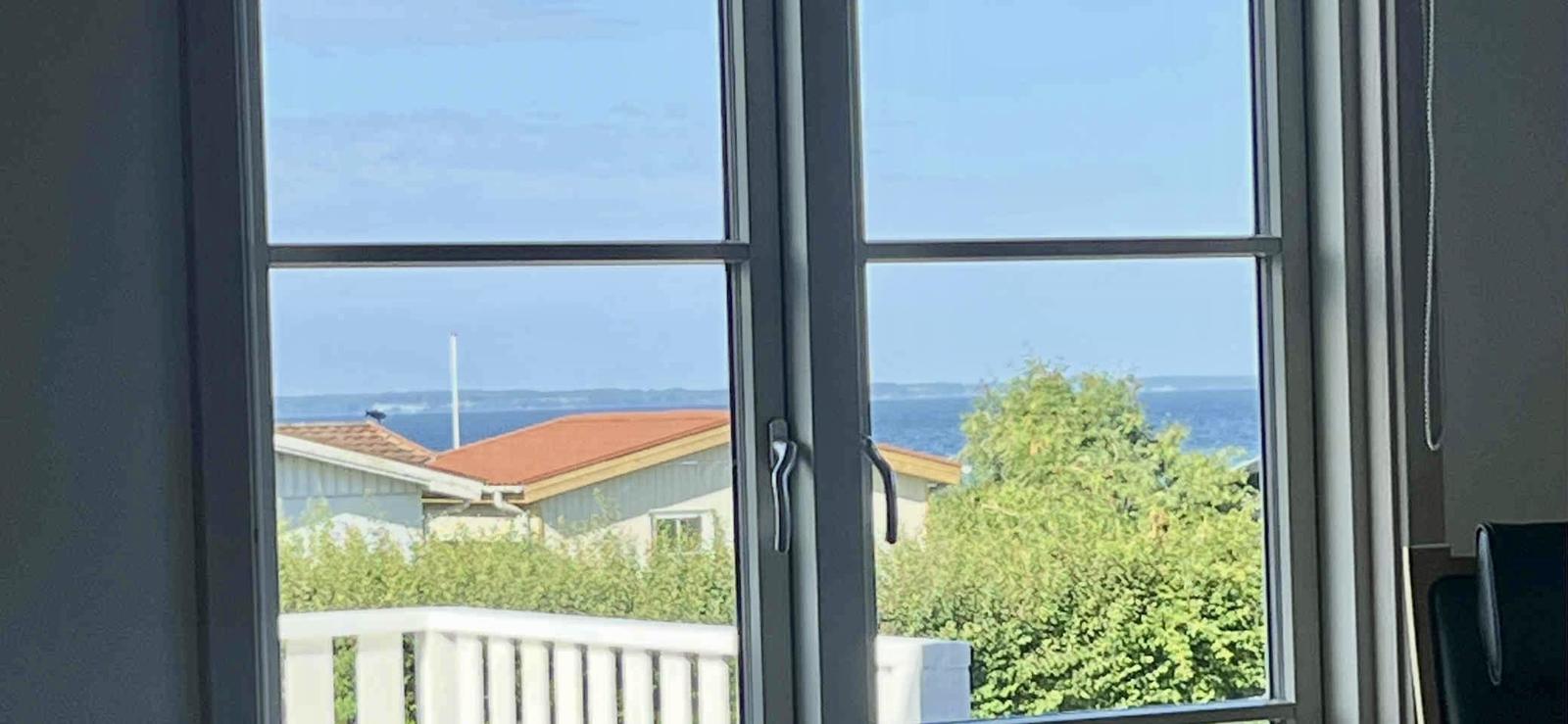 Durch das Fenster ist ein Blick auf das Meer und Häuser zu sehen.