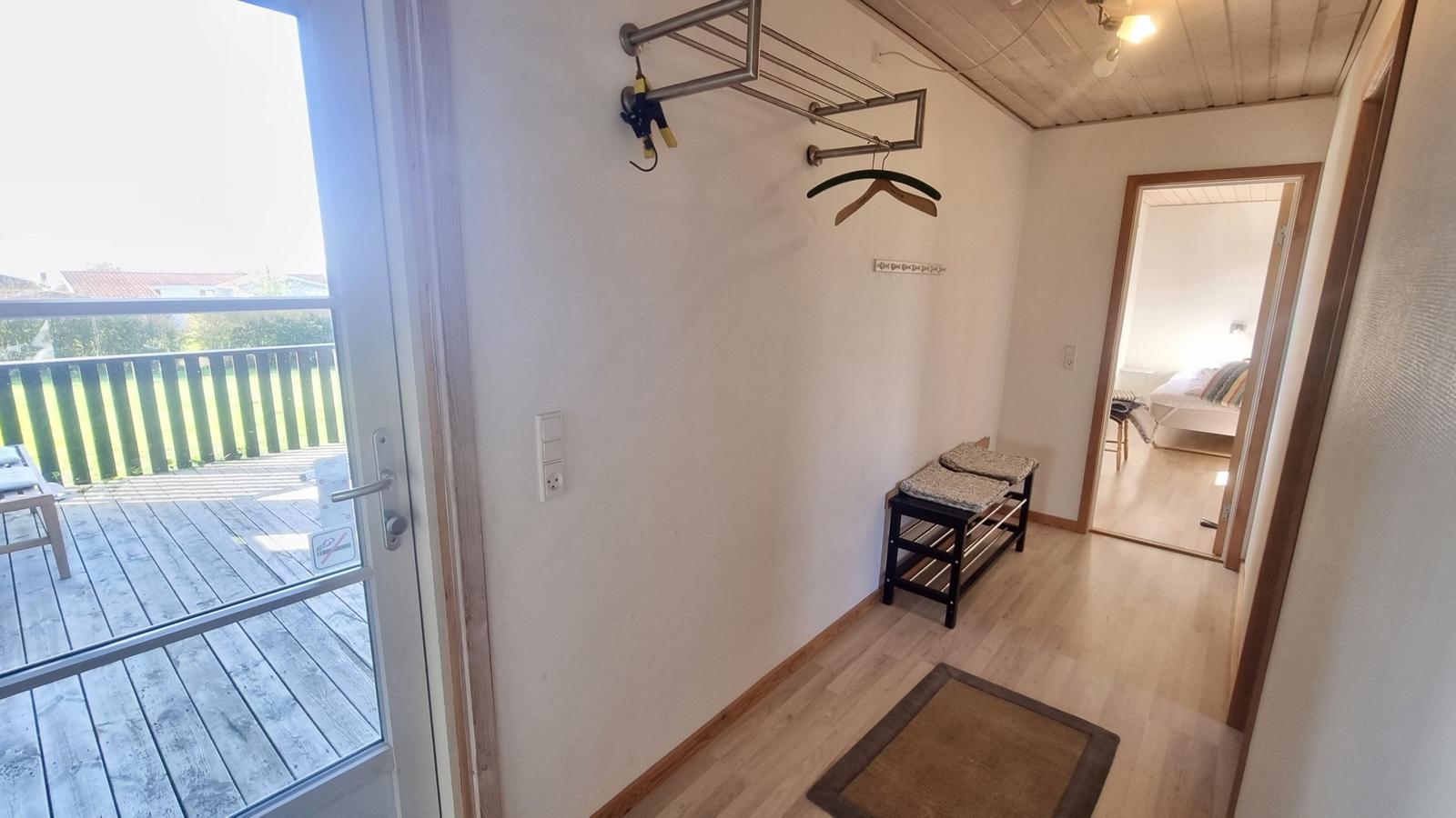 Eingangsbereich mit Garderobe, Sitzbank und Blick auf Balkon.