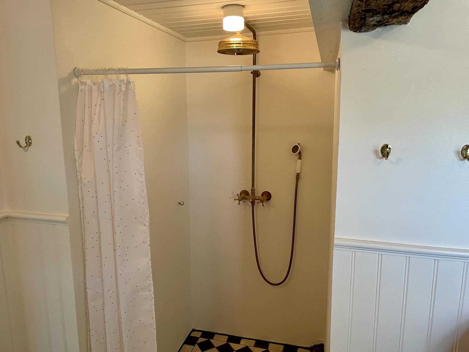 Dusche mit Duschvorhang, Duschkopf und Bodenfliesen