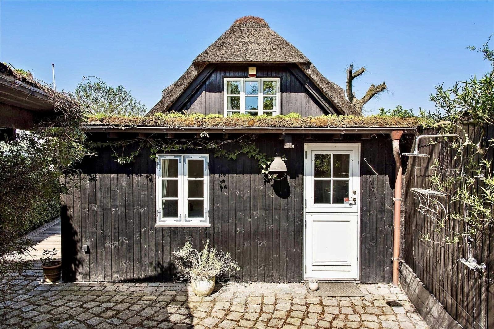 Holzhaus mit strohgedecktem Dach und weißer Tür