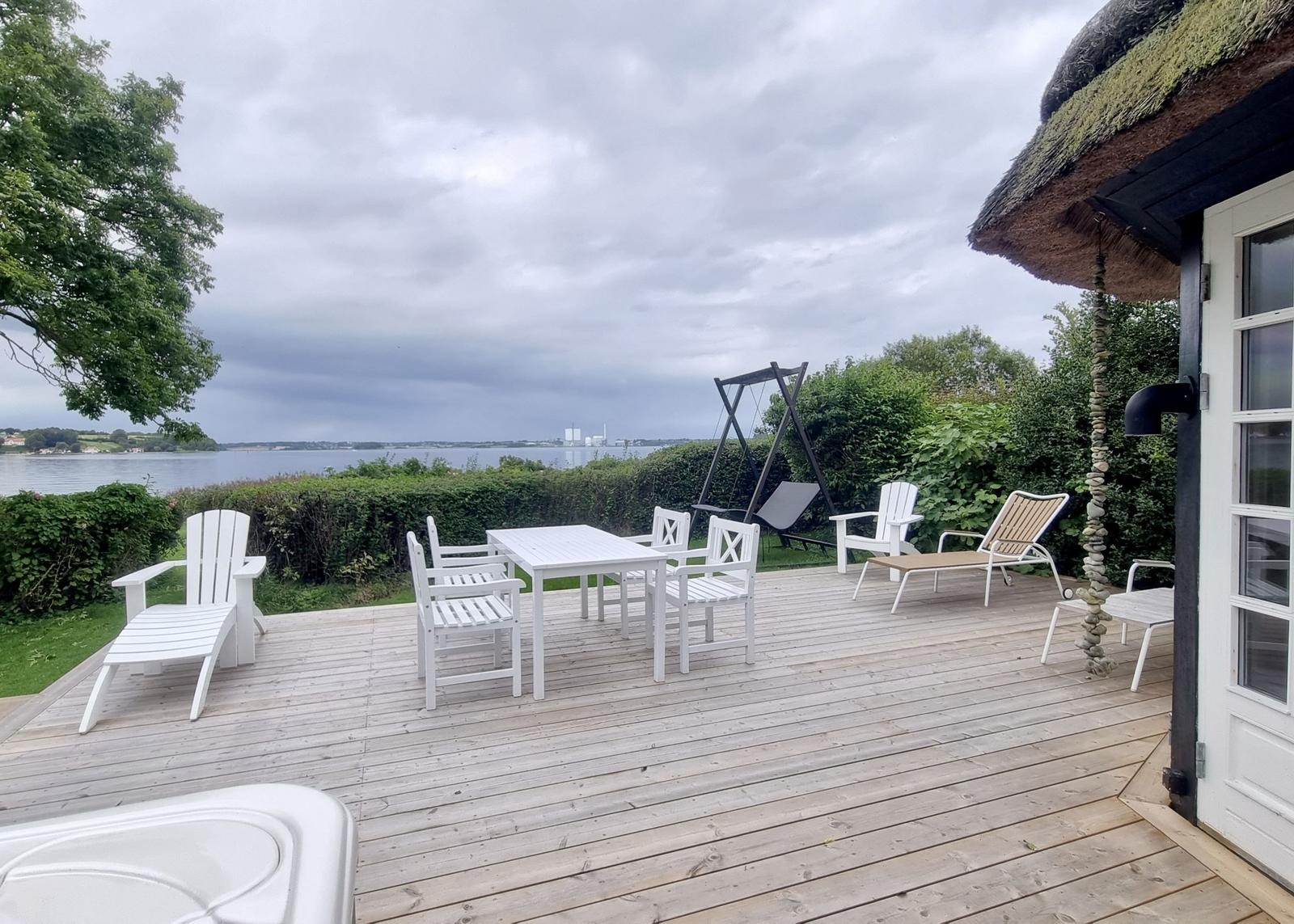 Terrasse mit Tisch, Stühlen und Blick auf Wasser