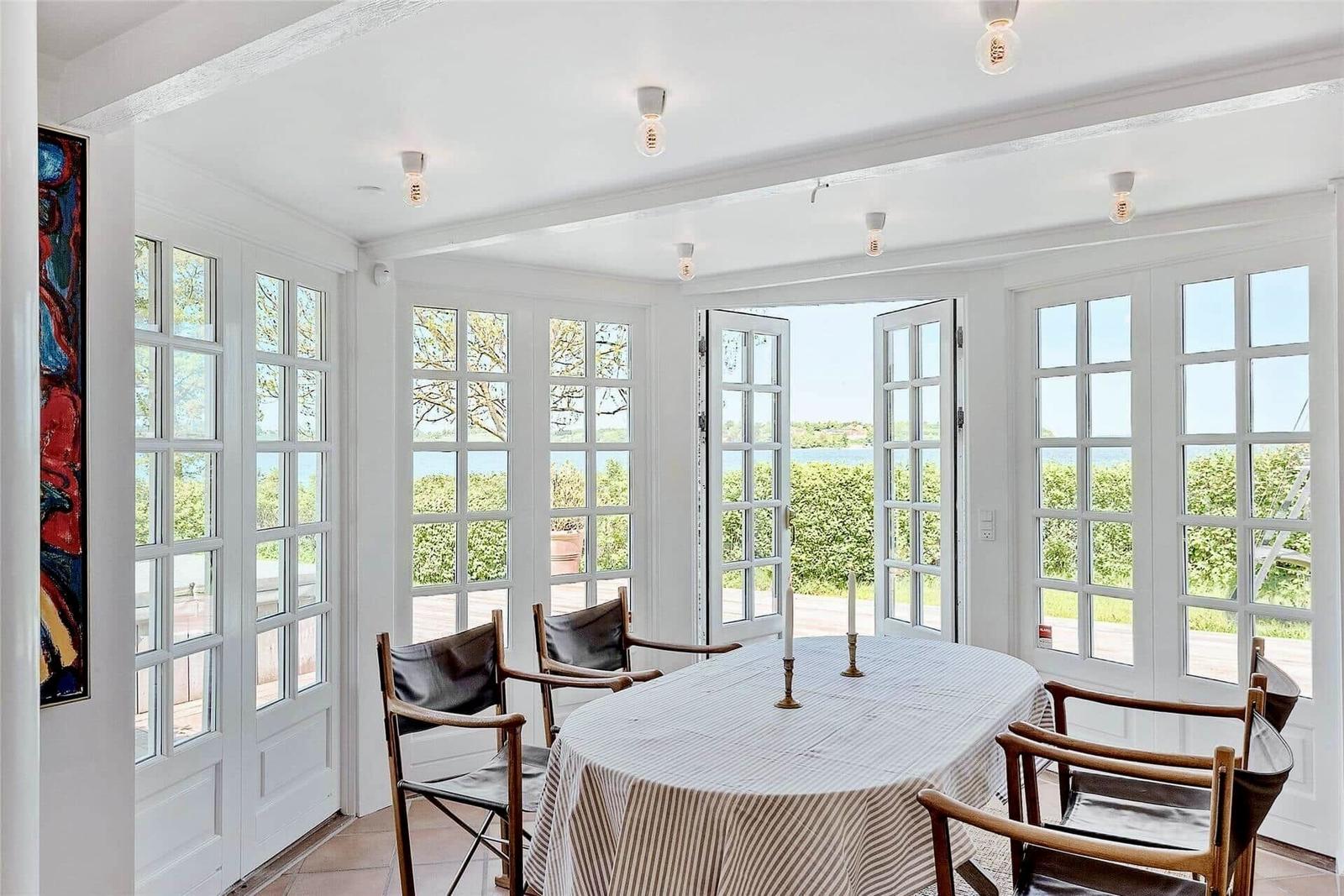 Esszimmer mit runden Tisch, Stühlen und Fenstern zum Garten.