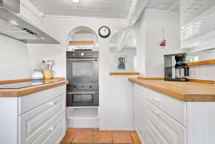 Küche mit Holzoberflächen, Edelstahlherd und Terrakottaboden.