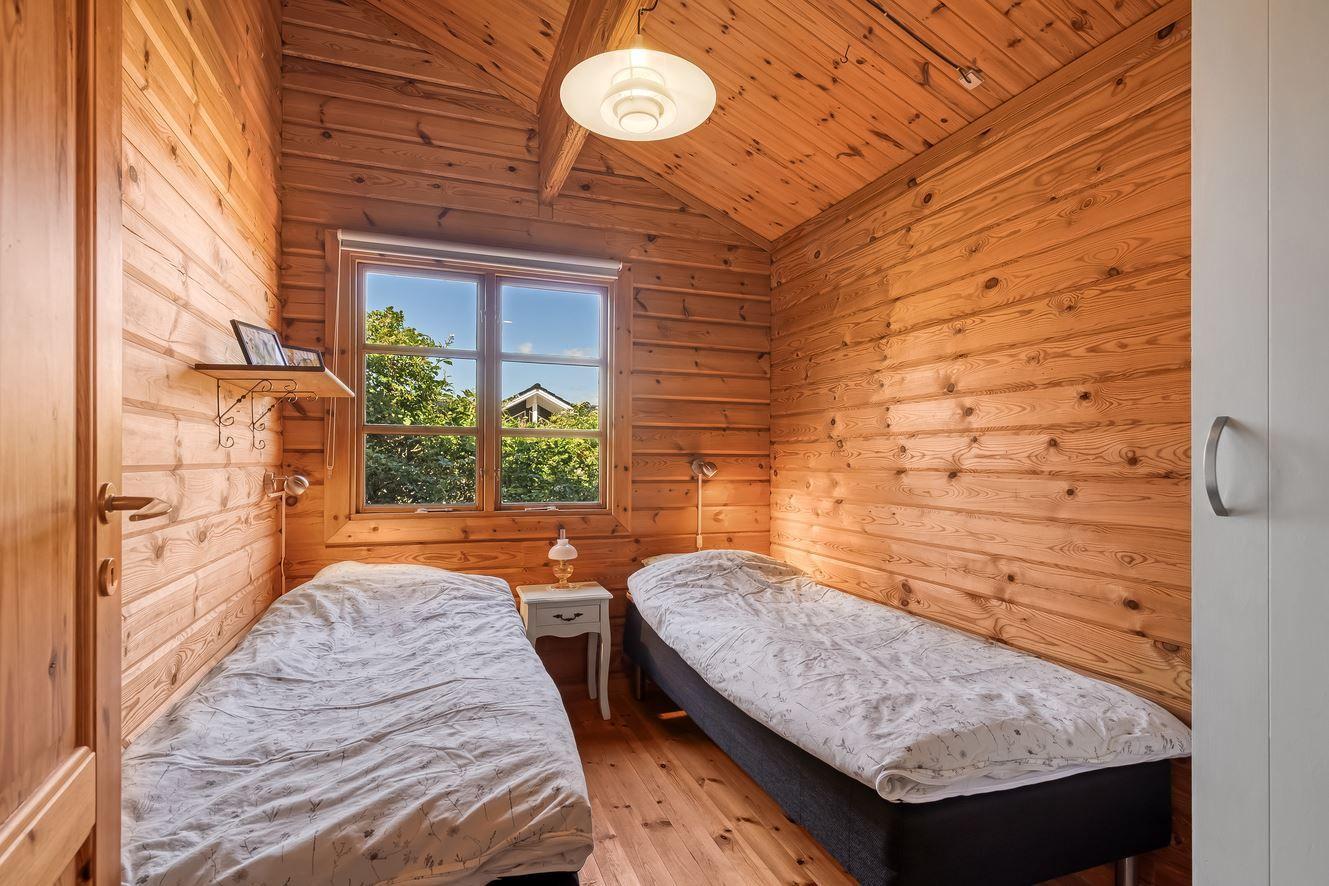 Zwei Betten in einem Holzraum mit Fenster und Nachttisch.