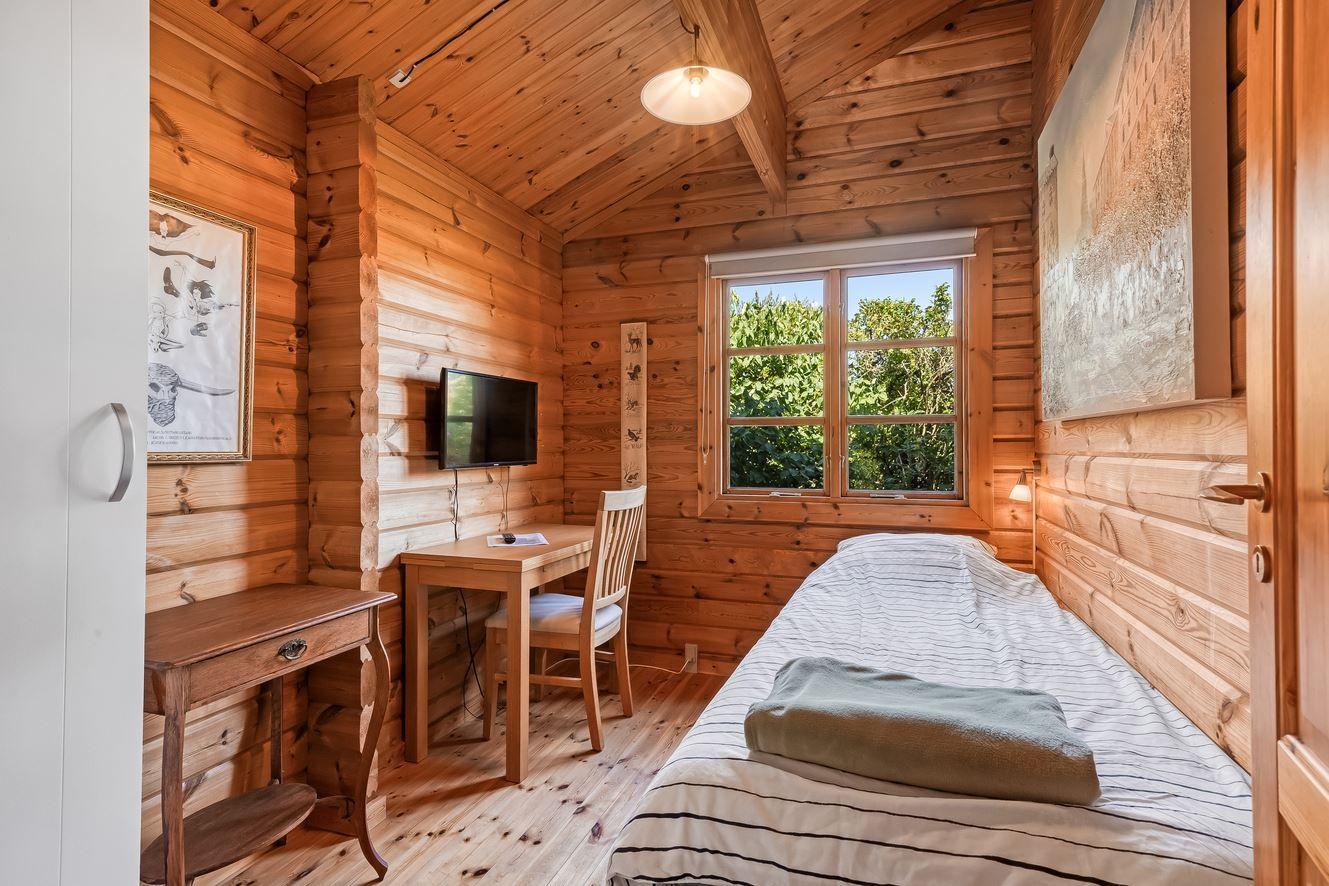 Ein Schlafzimmer mit Holzwand, Bett, Schreibtisch und Fernseher.