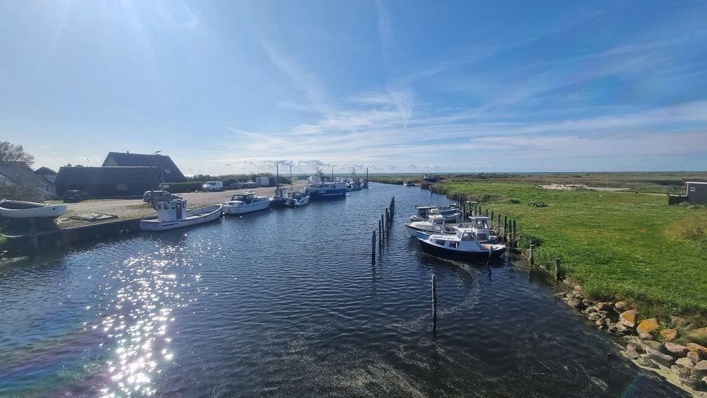 Schiff im Hafen mit grünen Ufern und blauem Himmel.