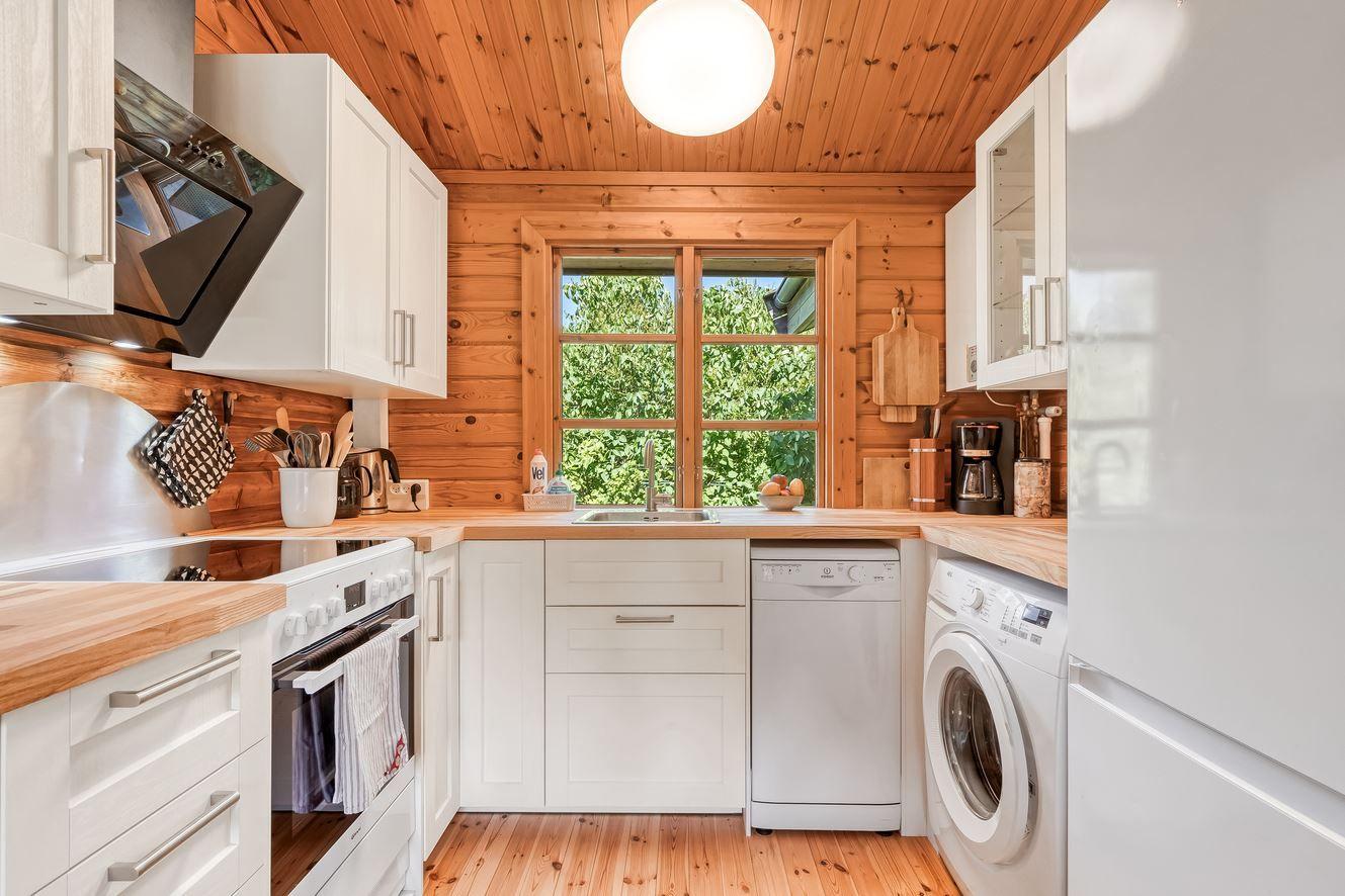 Küche mit Holzwand, Fenster, Spüle, Waschmaschine und Trockner.