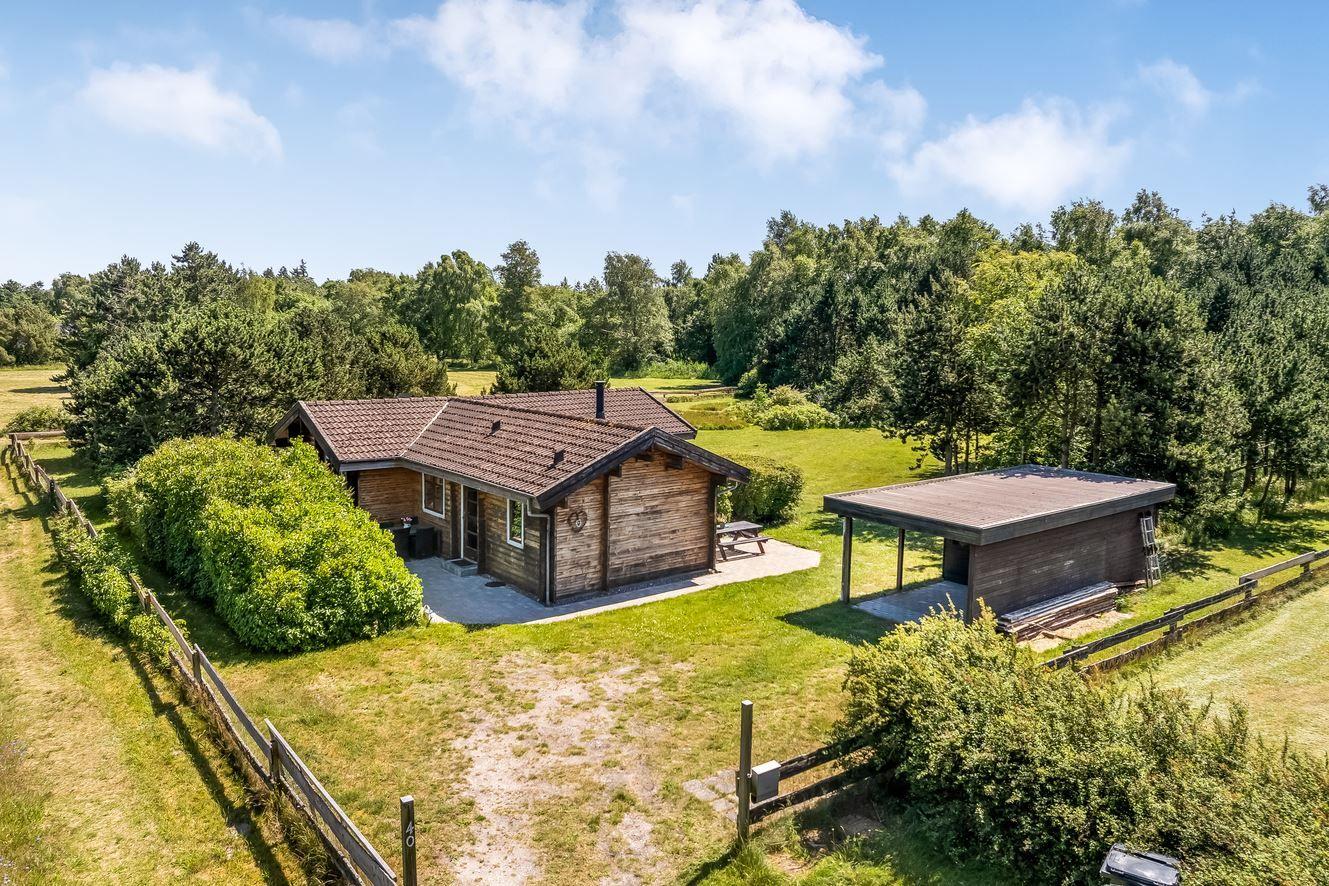 Holzhaus mit Terrasse und Garten in grüner Umgebung.