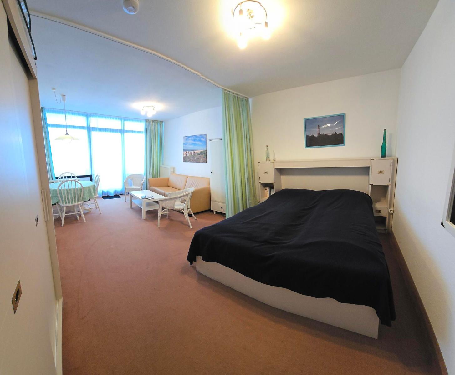 Schlafzimmer mit Bett und Wohnbereich mit Sofa und Tisch.