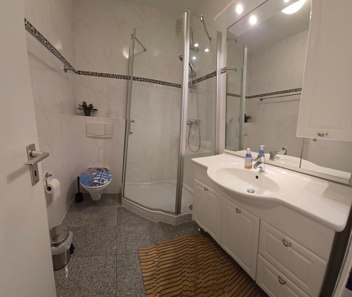 Badezimmer mit Dusche, Waschbecken und Toilette.