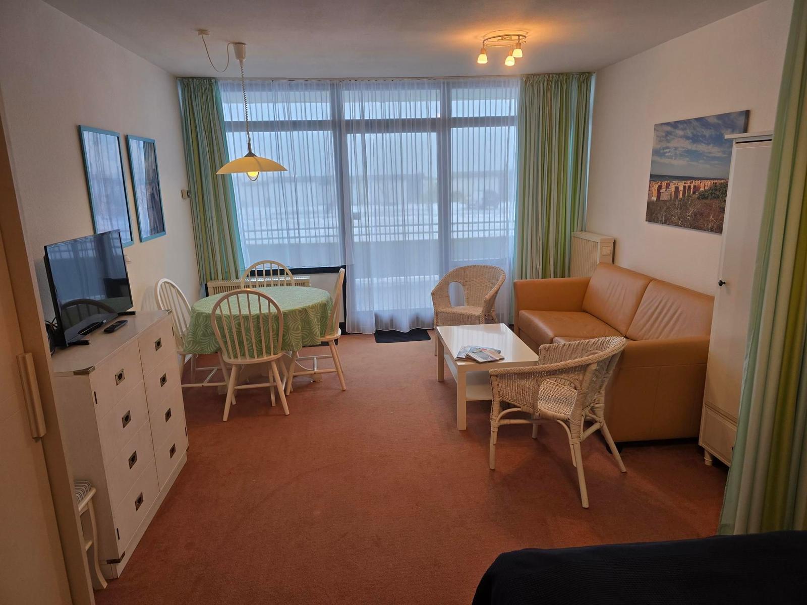 Wohn- und Essbereich mit Sofa, Esstisch und TV.