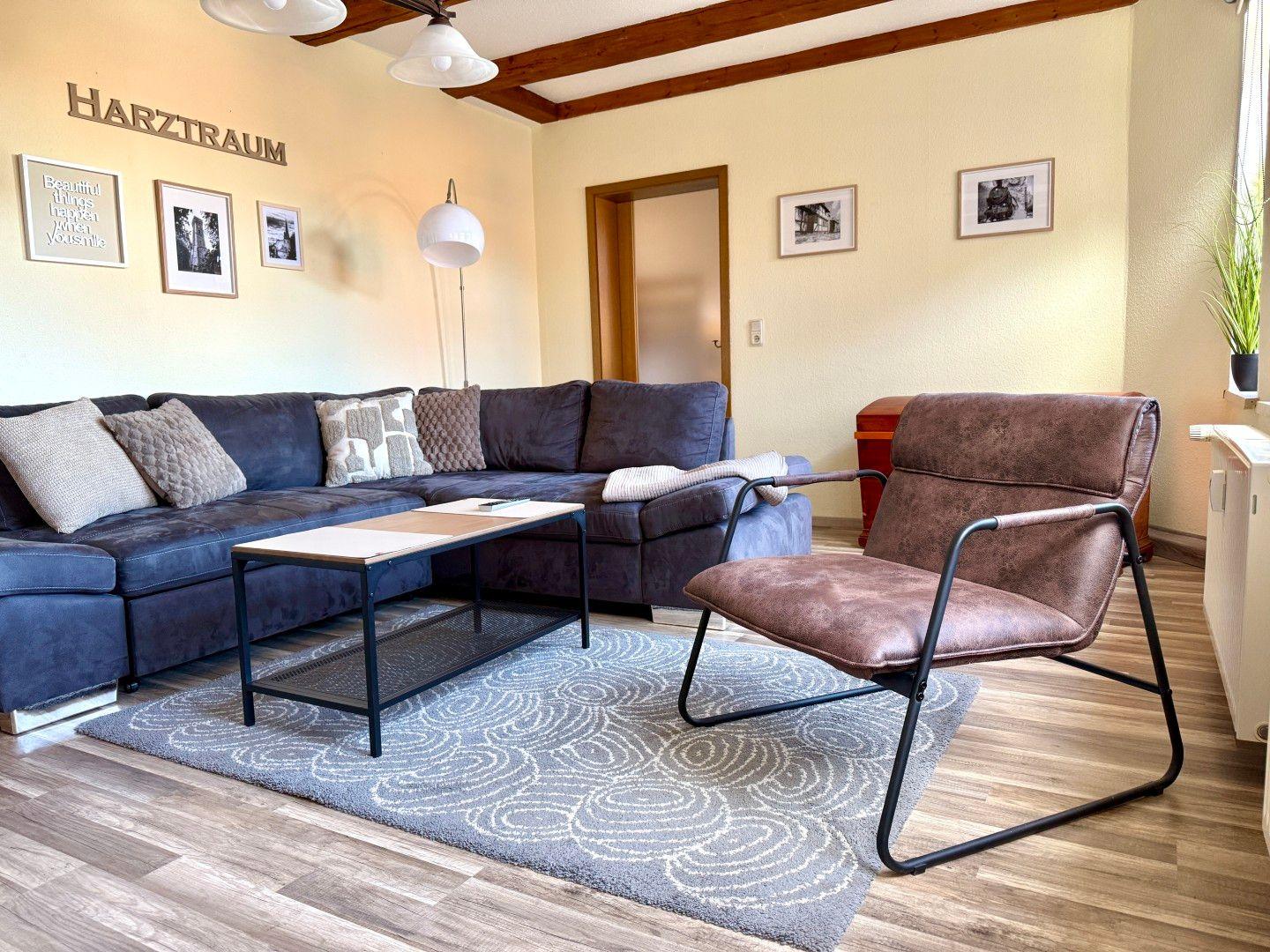 Heller Wohnbereich mit Ecksofa, Ledersessel und Holzbalken - gemütliches Wohnzimmer der Ferienwohnung Harztraum in Blankenburg Harz