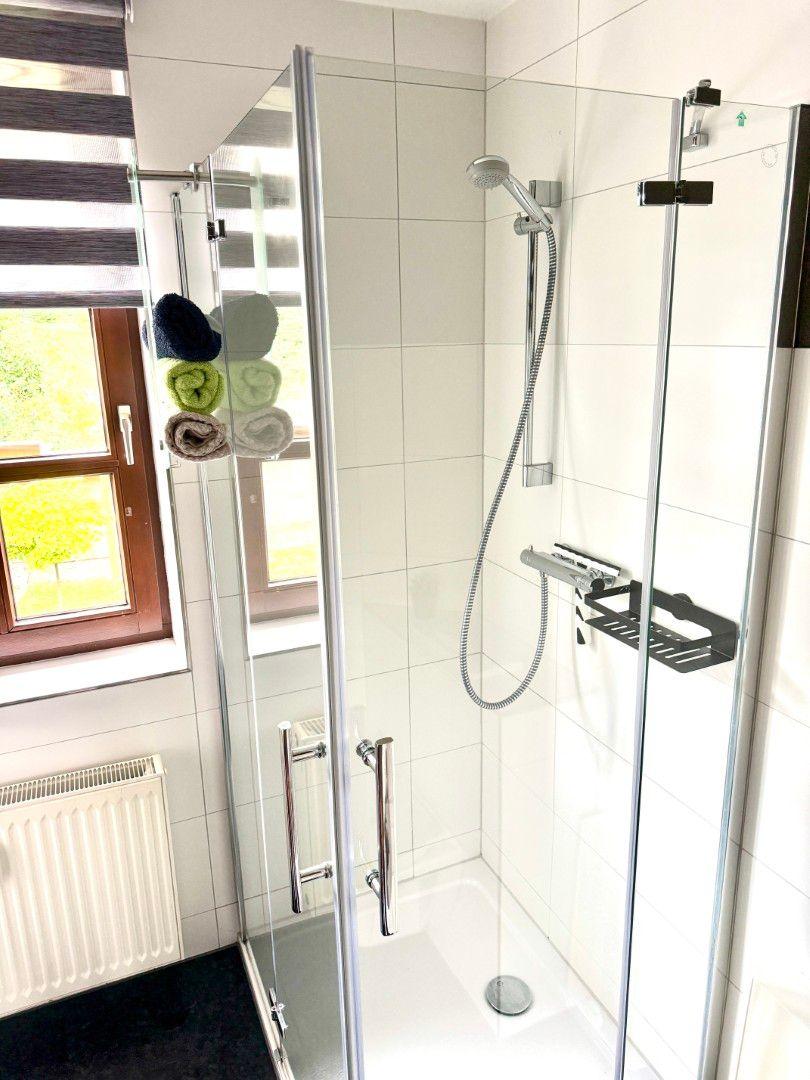 Badezimmer mit Dusche, Waschbecken und Fenster in der Ferienwohnung Harztraum an der alten Stadtmauer in Blankenburg