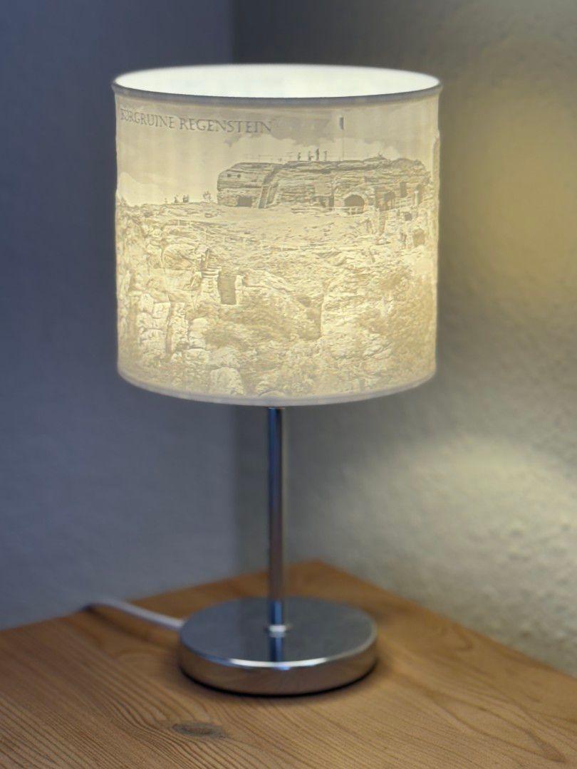Tischlampe mit Schirm, der Burg Ruine Regenstein zeigt, auf Holztisch.