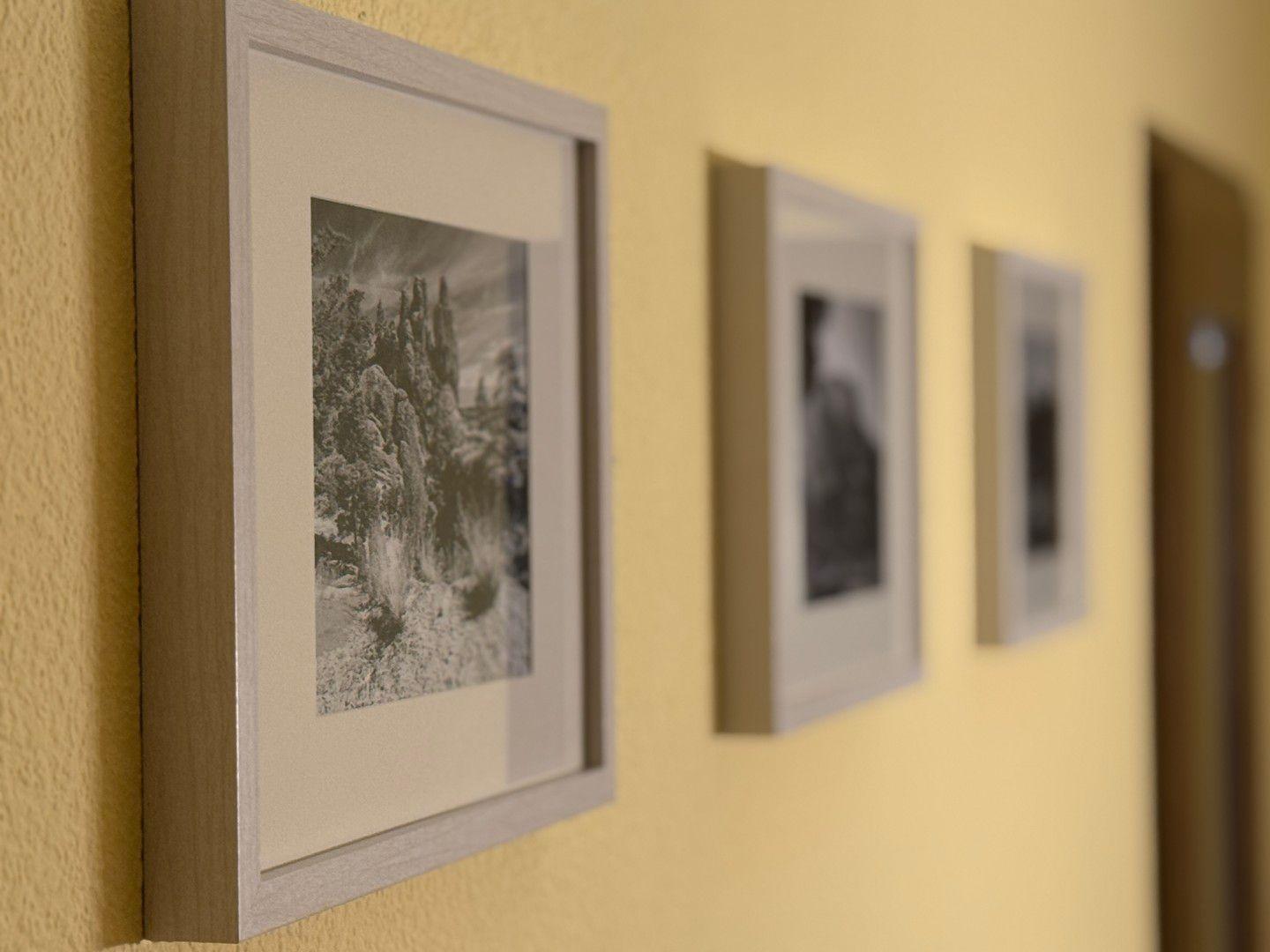 Wand mit drei gerahmten Schwarz-Weiß-Fotografien in hellen Rahmen.