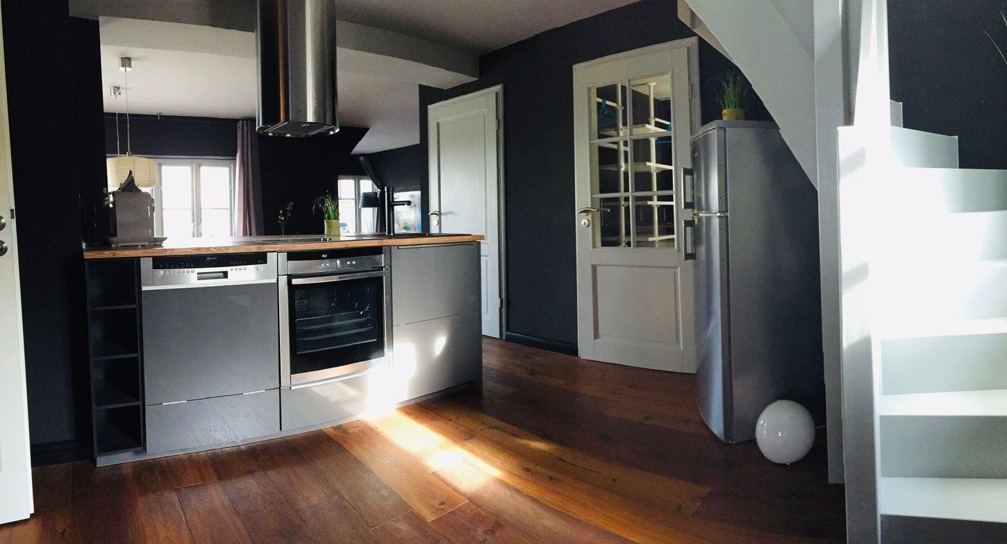 Küche mit Edelstahlgeräten, Holzboden und Treppe zur oberen Etage.