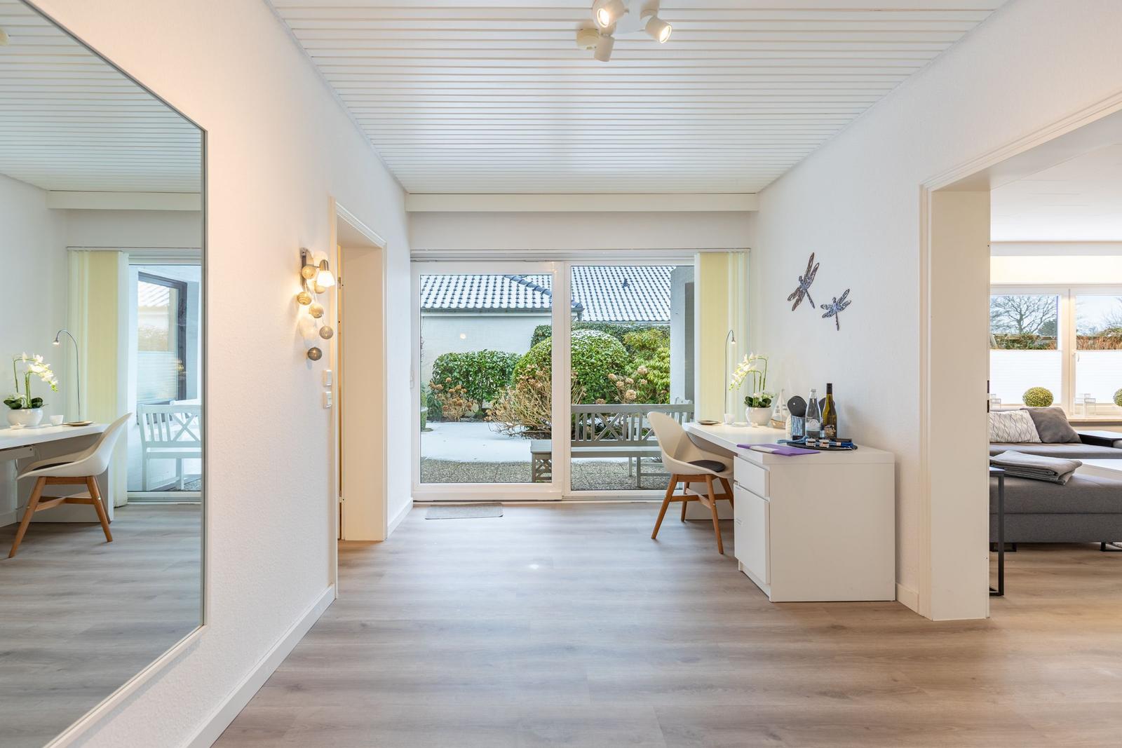 Helle Wohnung mit Blick auf Garten und Terrasse. Schreibtisch, Spiegel und Schlafzimmer sichtbar.
