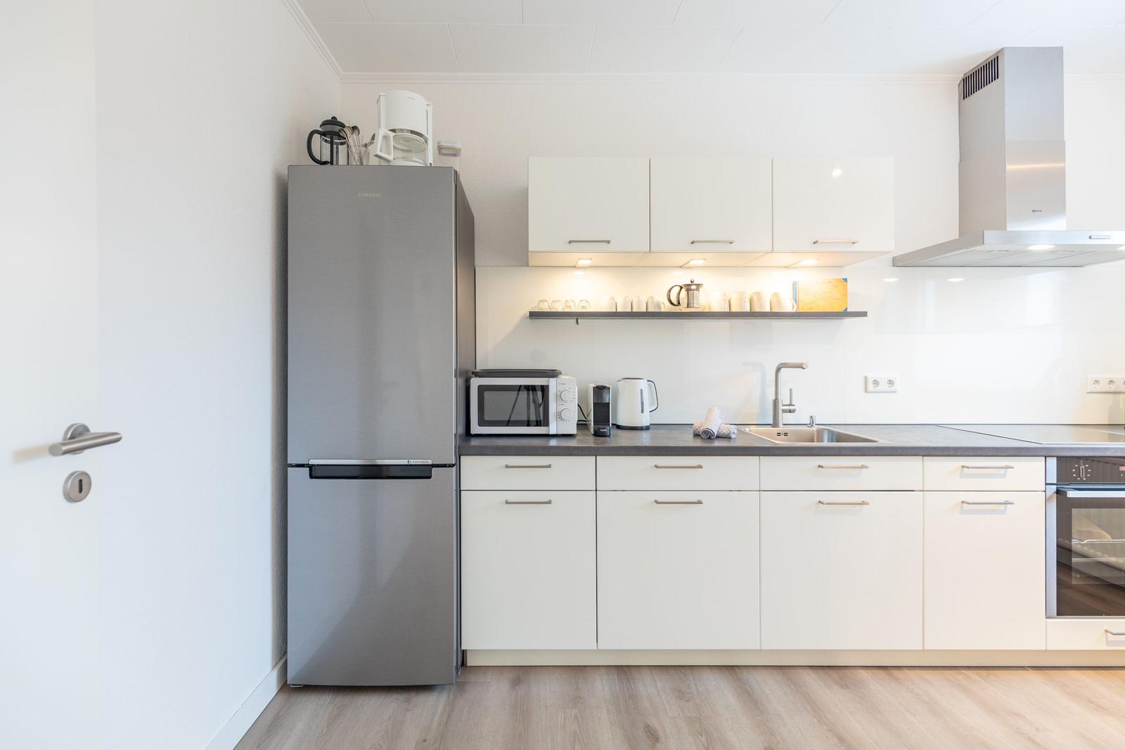 Küche mit Kühlschrank, Dunstabzug und Arbeitsfläche