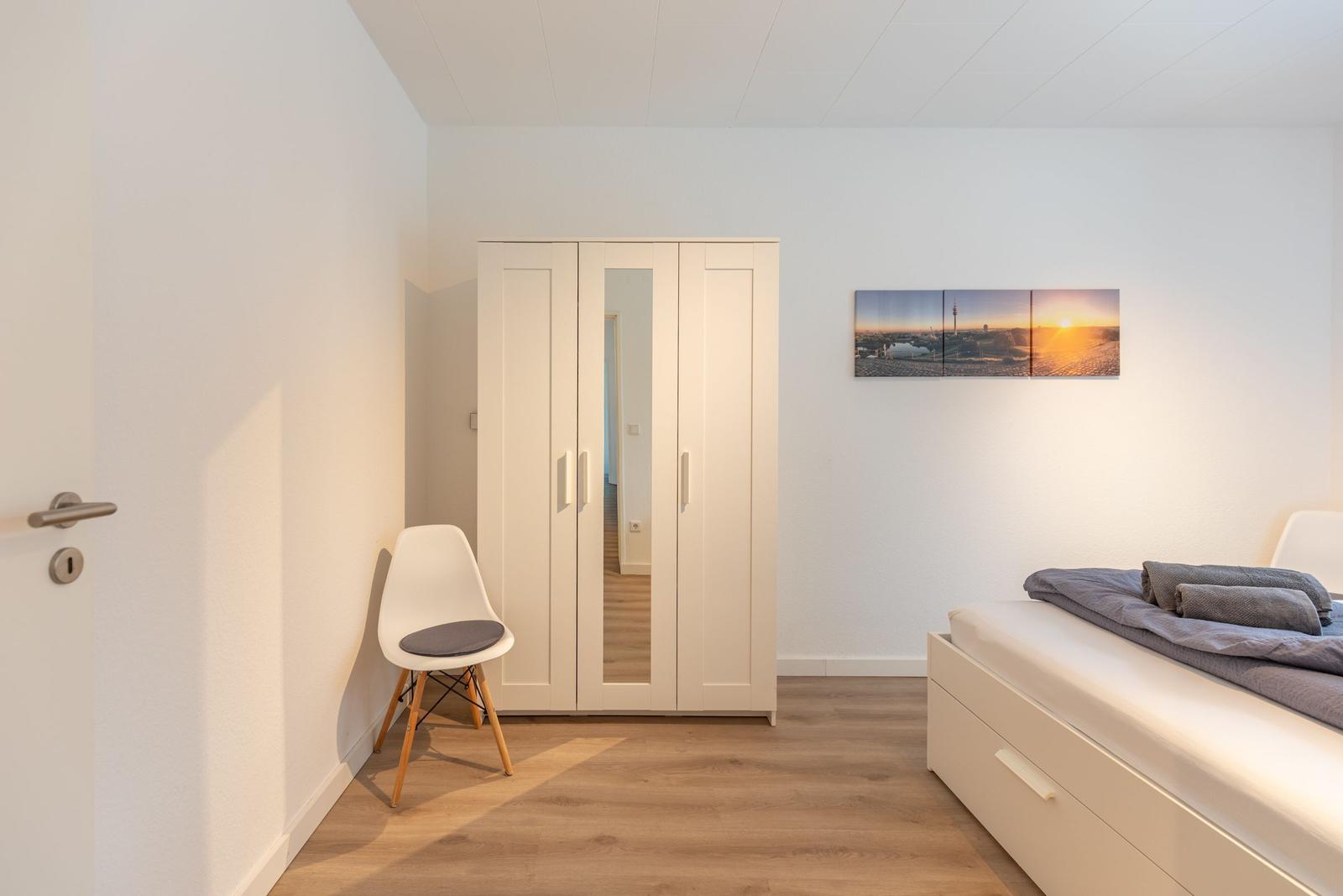 Schlafzimmer mit Bett, Kleiderschrank und Wandbild.