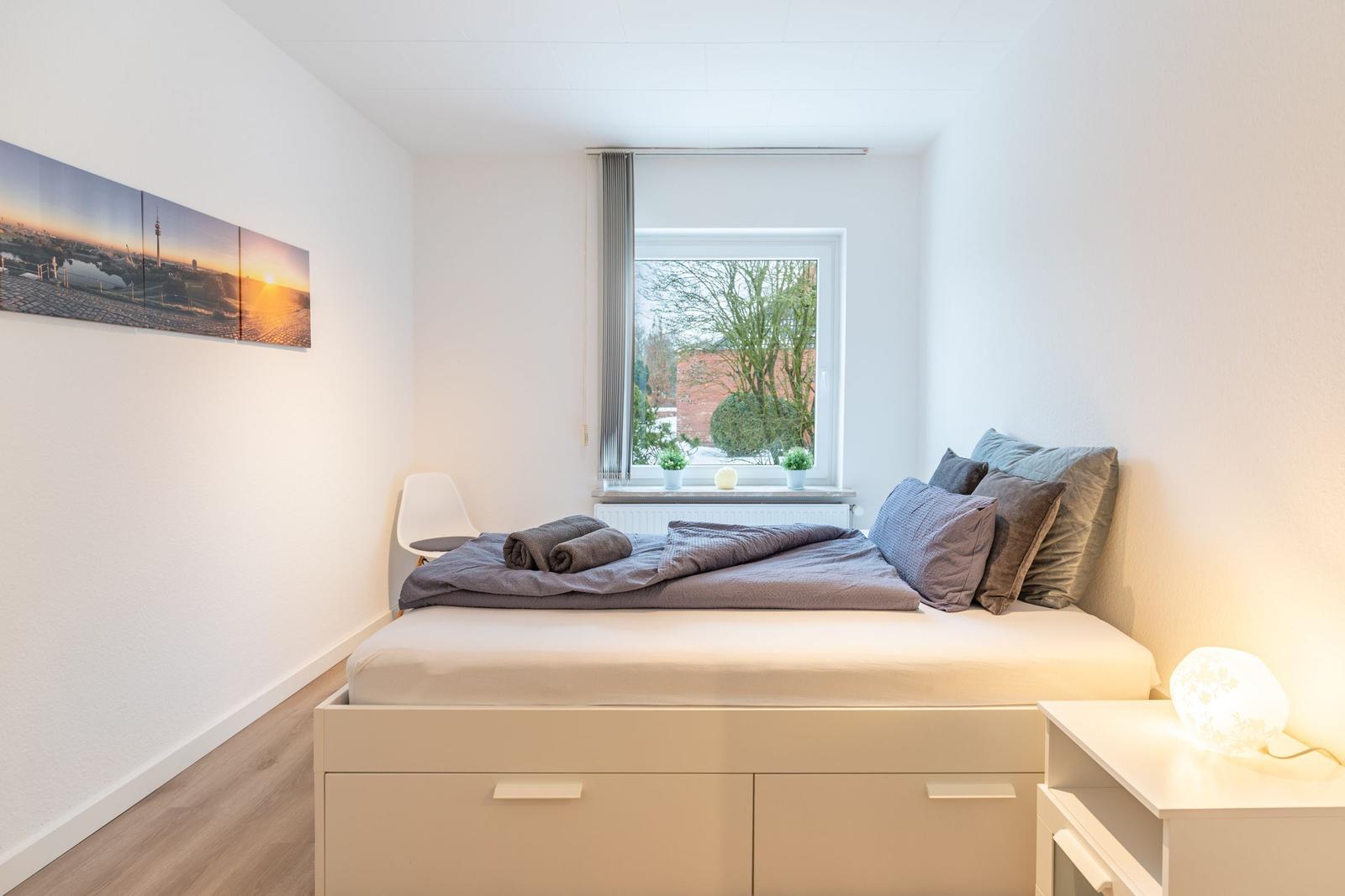 Schlafzimmer mit Bett, Fenster und Wandbild.