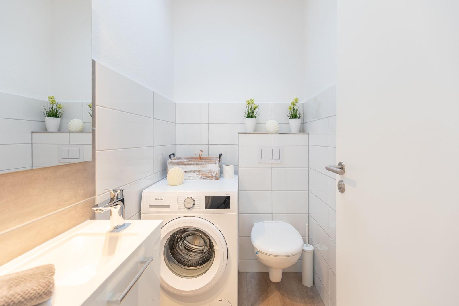 Badezimmer mit Waschmaschine, Toilette und Spiegel