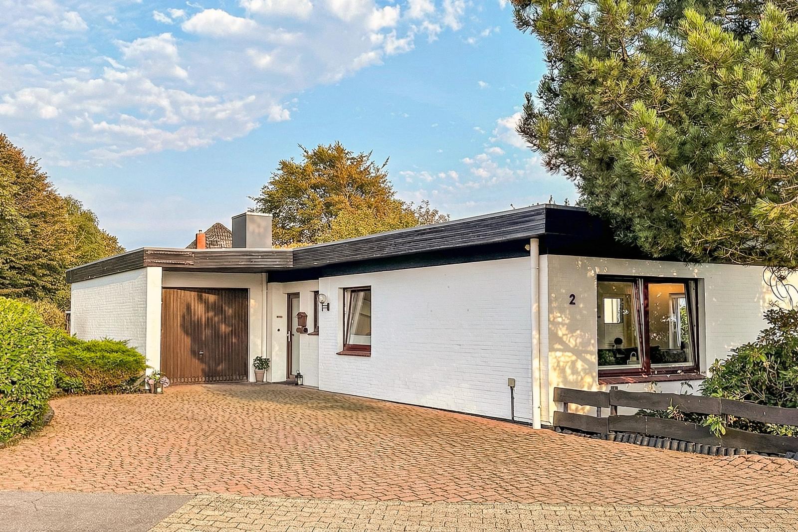 Moderne weiße Villa mit Garage und Terrasse im Grünen.