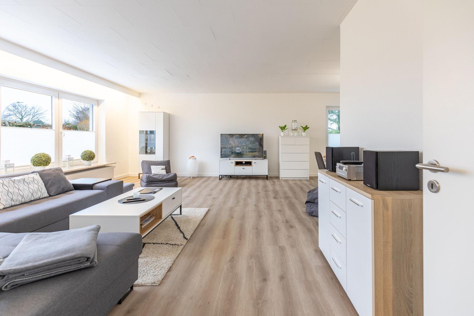 Wohnzimmer mit Sofa, TV und Holzboden.
